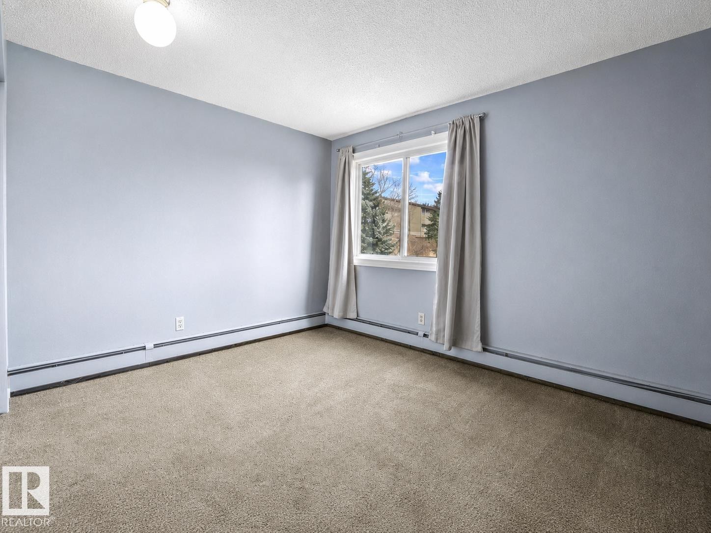 Neutral-toned carpeting, light-colored wall paint, overhead flush-mount lighting, and a window with white trim - #1 13450 Fort Rd Nw, Edmonton, AB - Indoor Photo Showing Other Room