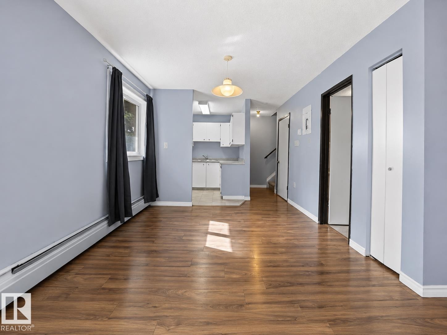Wood-finish flooring throughout, white baseboards, and a window with curtains - #1 13450 Fort Rd Nw, Edmonton, AB - Indoor Photo Showing Other Room