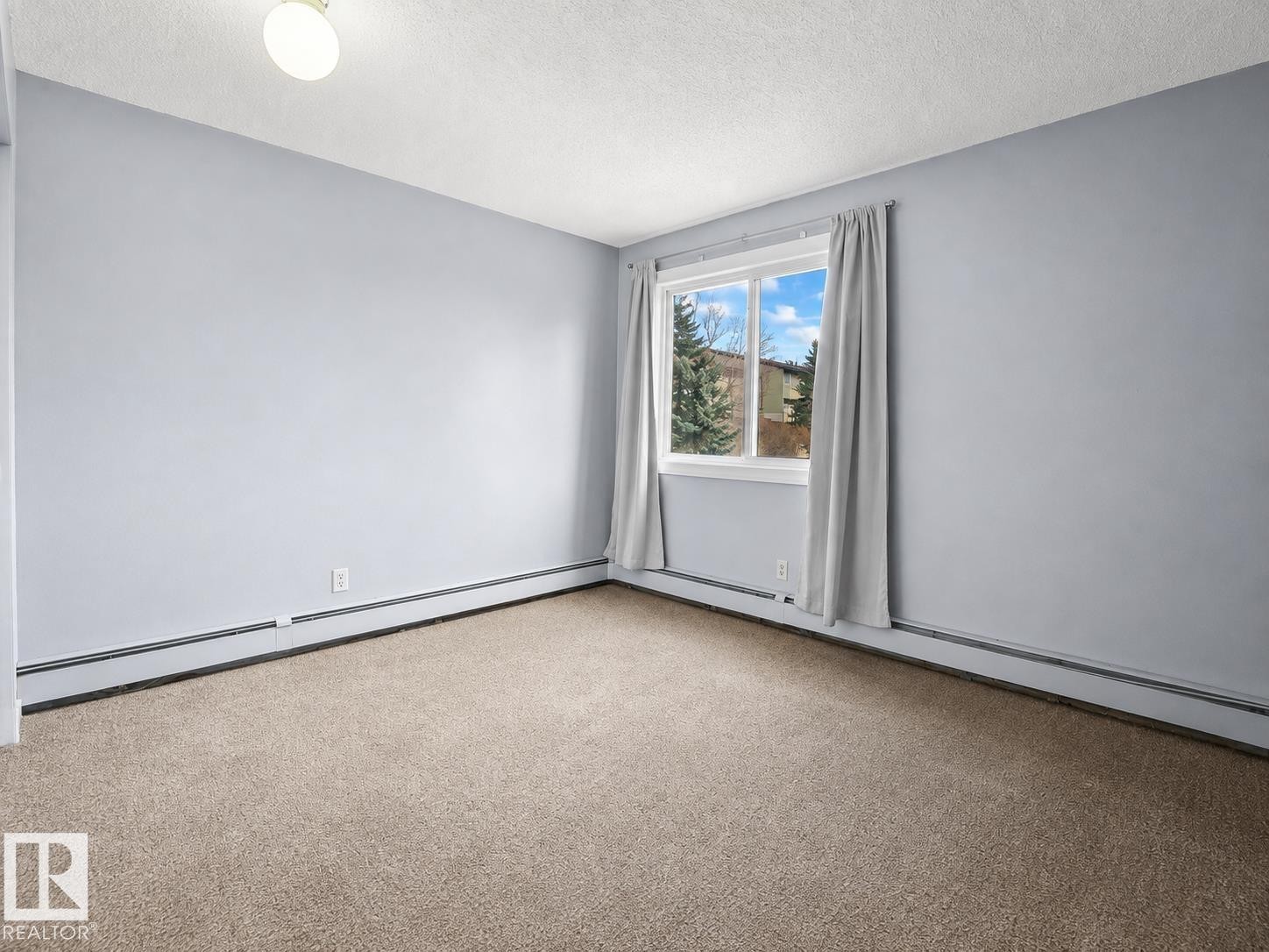Wall-to-wall carpeting, window with natural scenery, and built-in baseboard heating - #1 13450 Fort Rd Nw, Edmonton, AB - Indoor Photo Showing Other Room