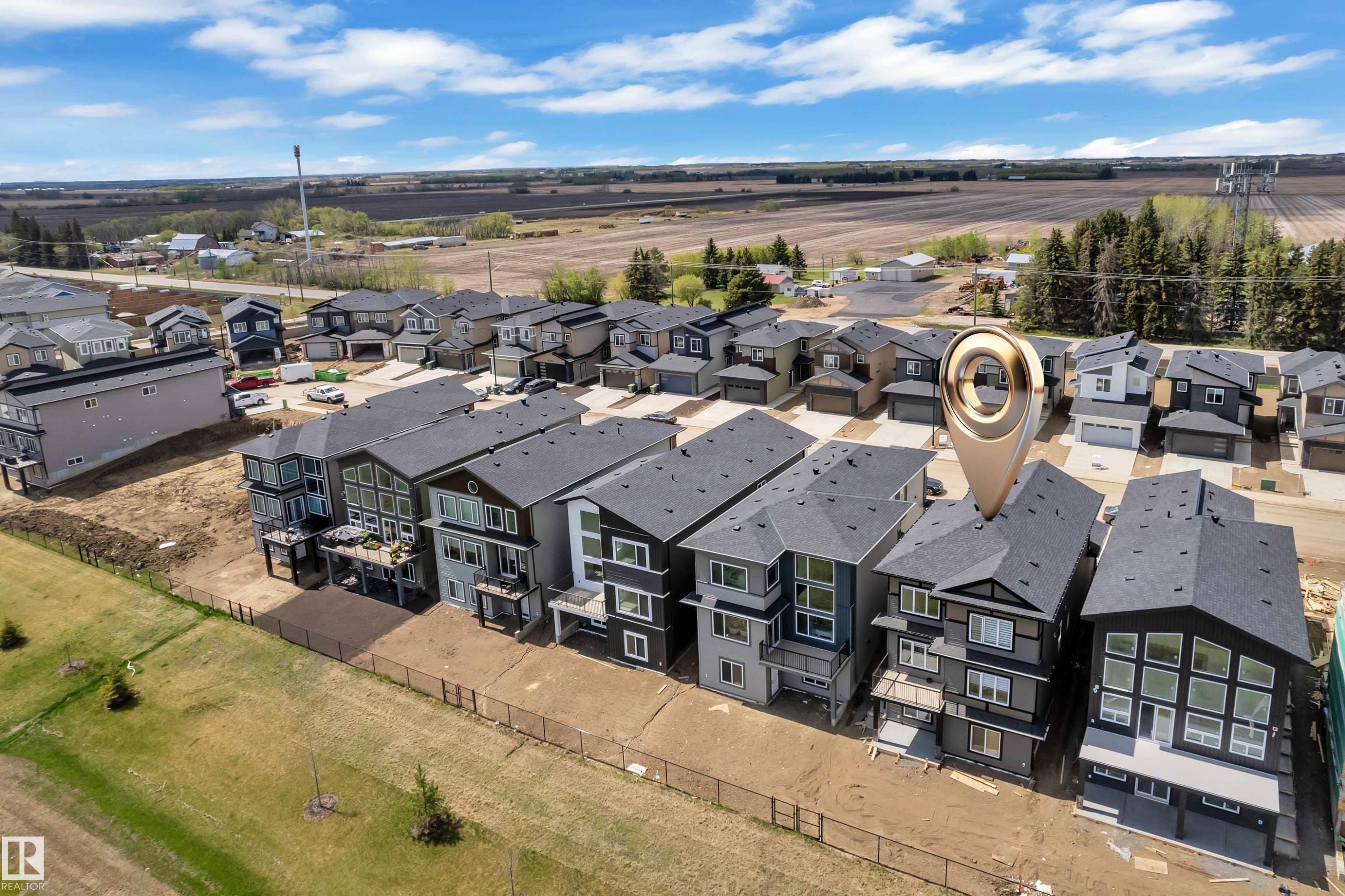 Modern residential development featuring multi-story homes with dark shingle roofs, contrasting exterior siding, and multiple windows - 228 Linden Loop, Leduc, AB