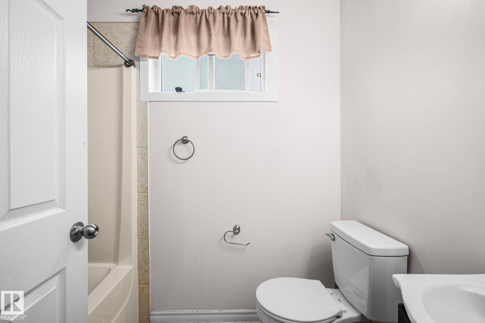 White interior walls with a white toilet and a separate bathtub - 4806 117 Ave, Edmonton, AB