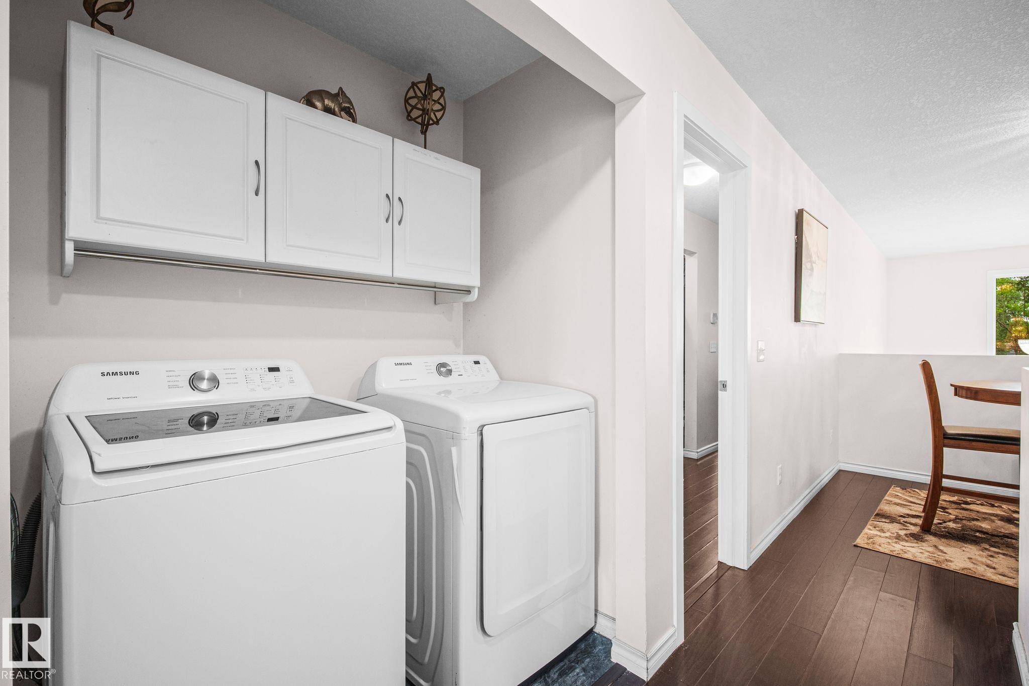 Dedicated laundry area featuring white wall cabinetry with brushed nickel hardware, and dark wood-finish flooring - 4806 117 Ave, Edmonton, AB
