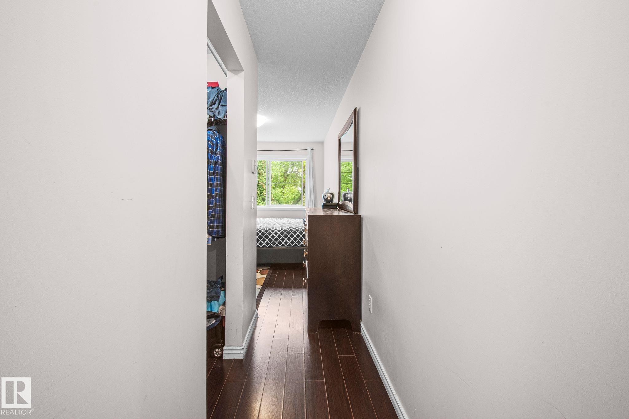 Hallway featuring dark wood-finish flooring, light-toned walls, and white trim - 4806 117 Ave, Edmonton, AB