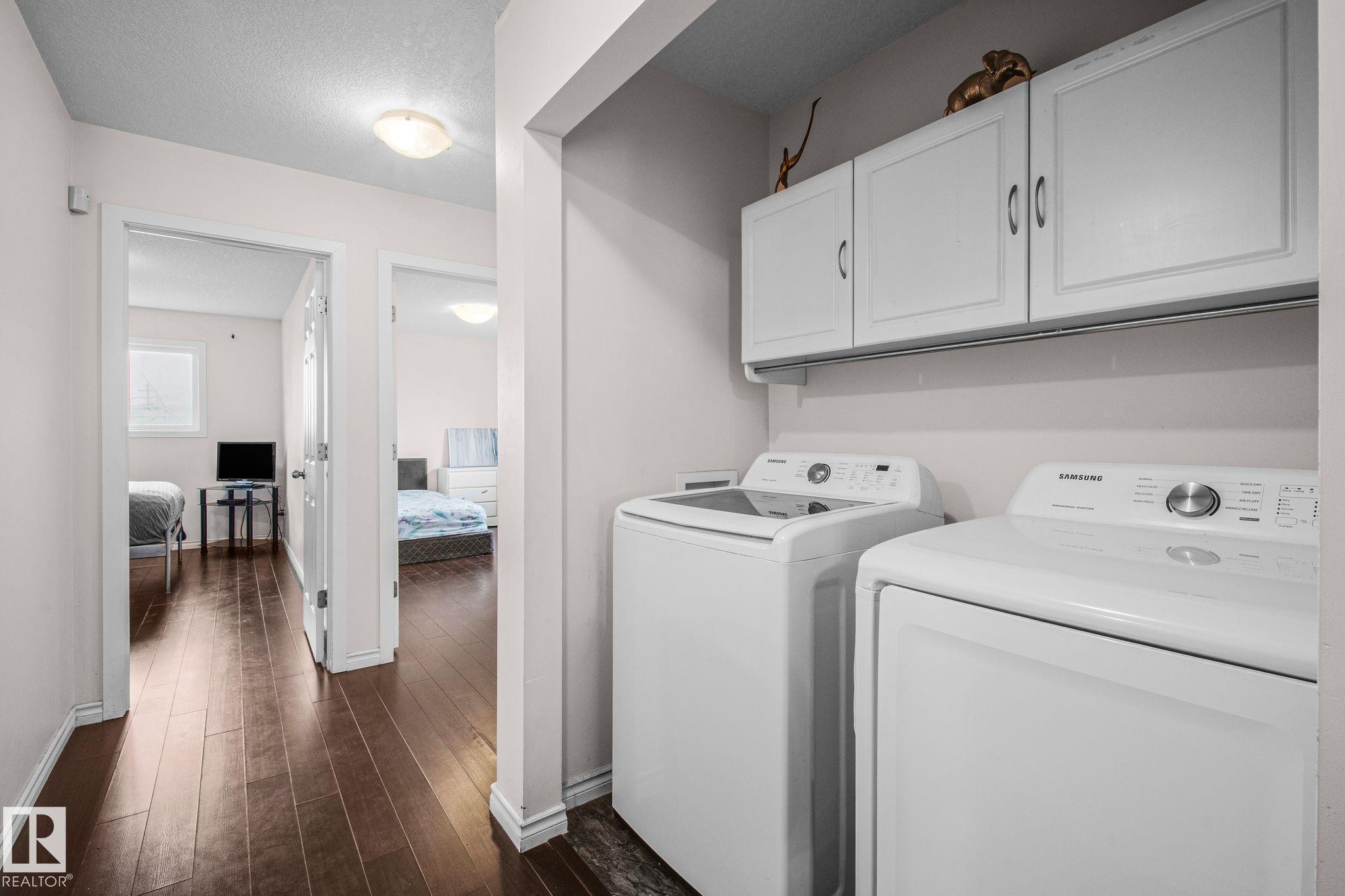 Dedicated laundry area featuring white upper cabinetry and a dark wood-finish flooring - 4806 117 Ave, Edmonton, AB