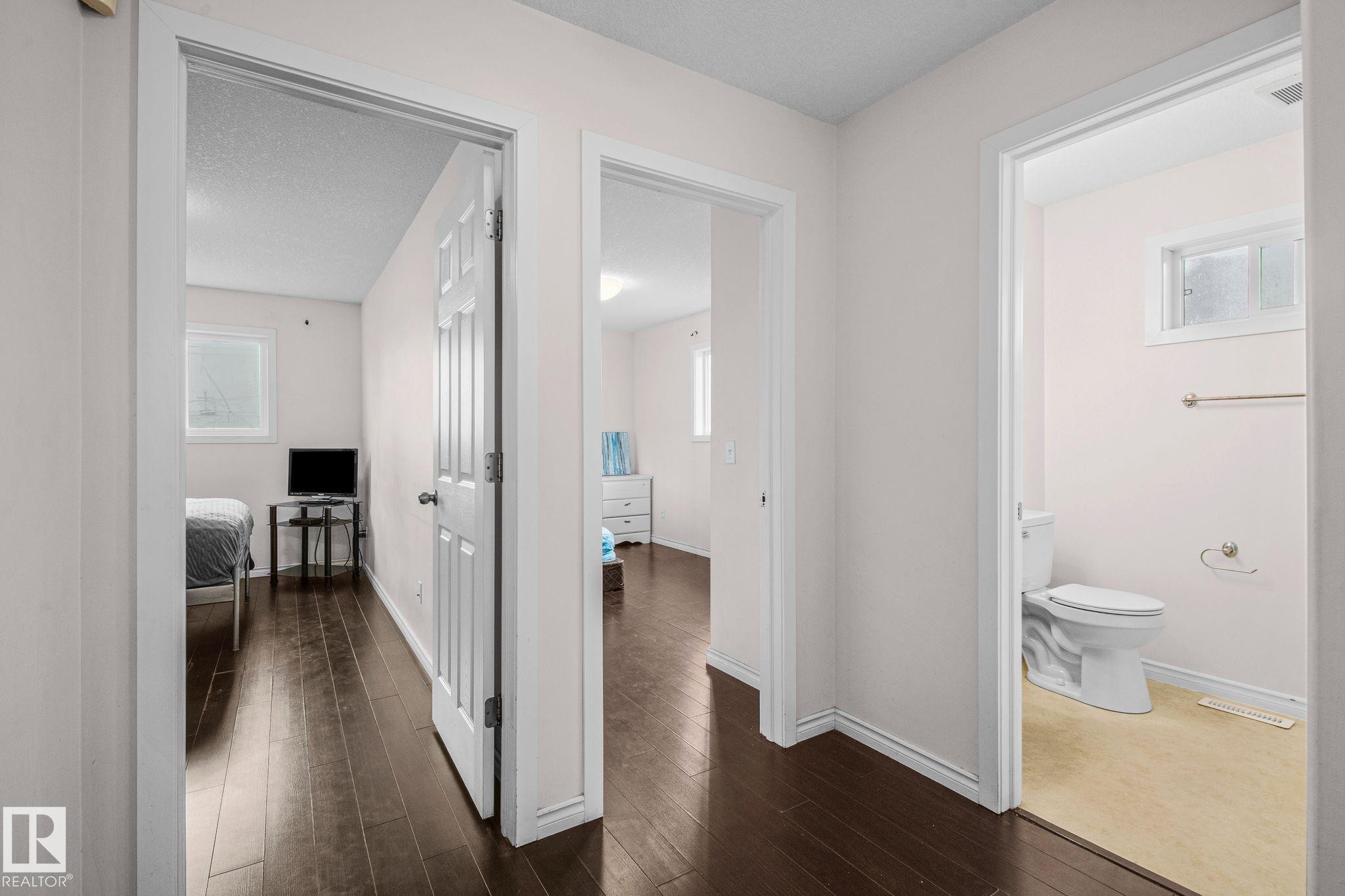 Hallway featuring dark wood-finish flooring, white baseboards, and light-colored walls - 4806 117 Ave, Edmonton, AB