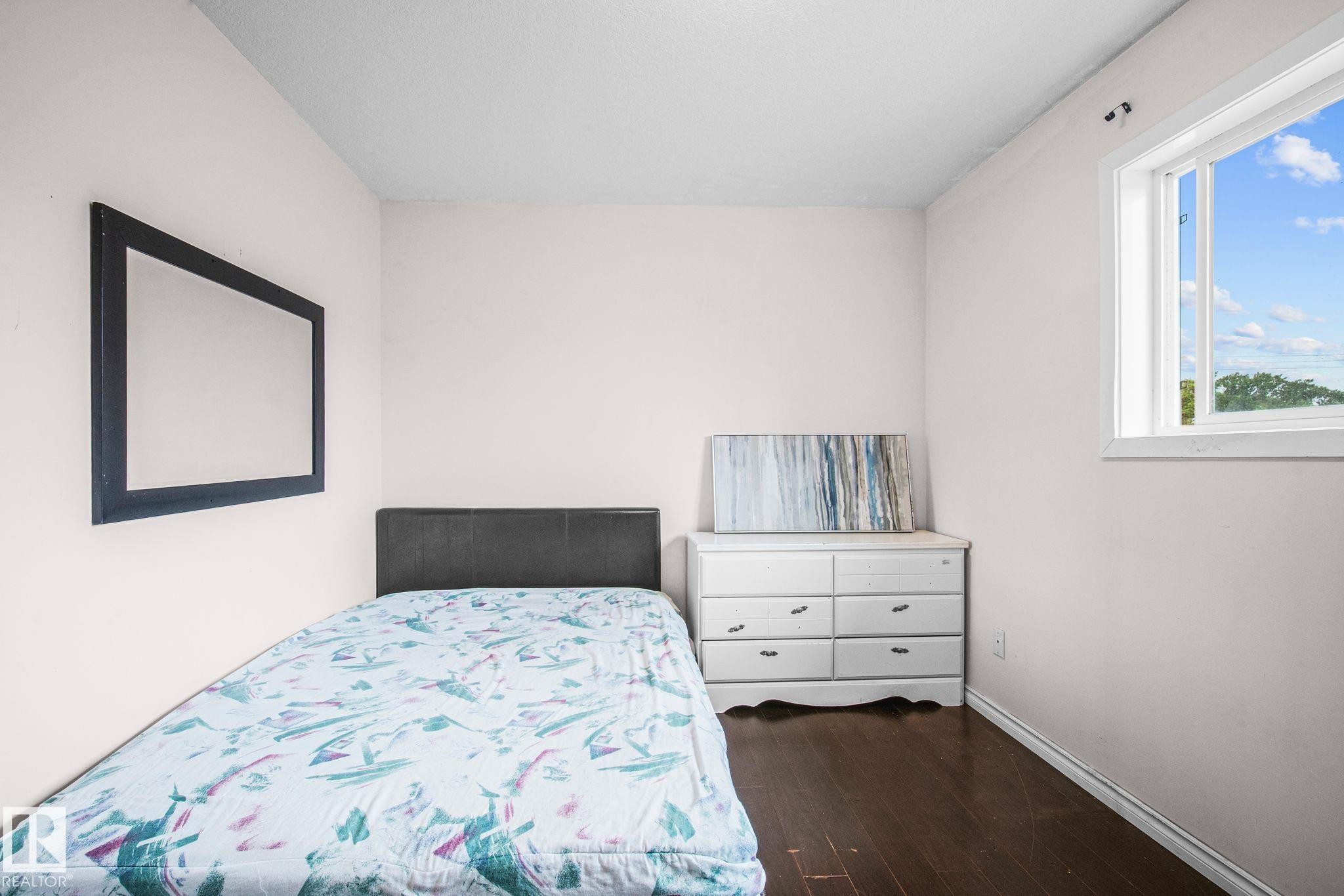 Room featuring a single window with white trim, wood-finish flooring, and light-toned walls - 4806 117 Ave, Edmonton, AB