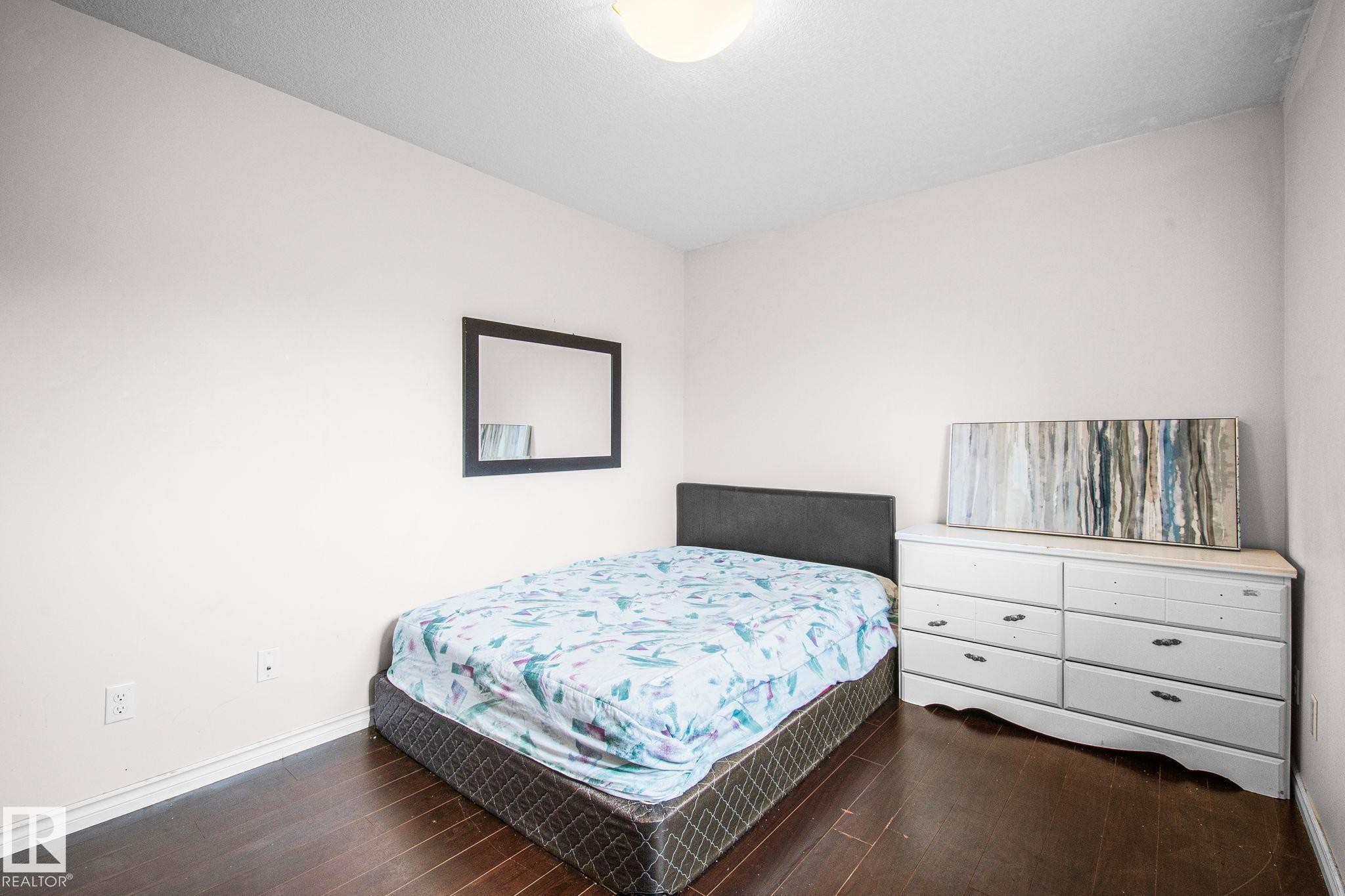 Bedroom featuring dark wood-finish flooring, light-toned walls, and a ceiling-mounted light fixture - 4806 117 Ave, Edmonton, AB