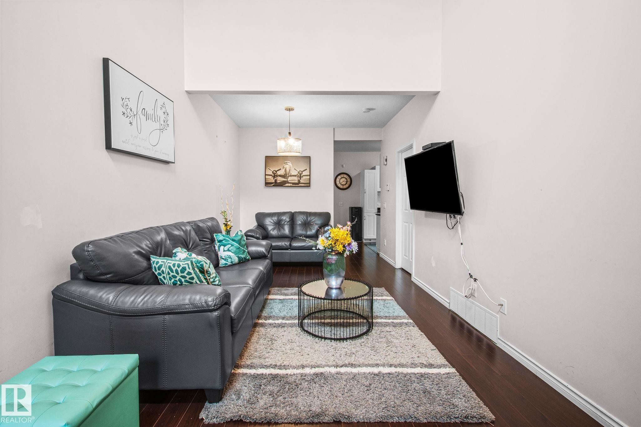 Living area featuring high ceilings and dark wood-finish flooring - 4806 117 Ave, Edmonton, AB