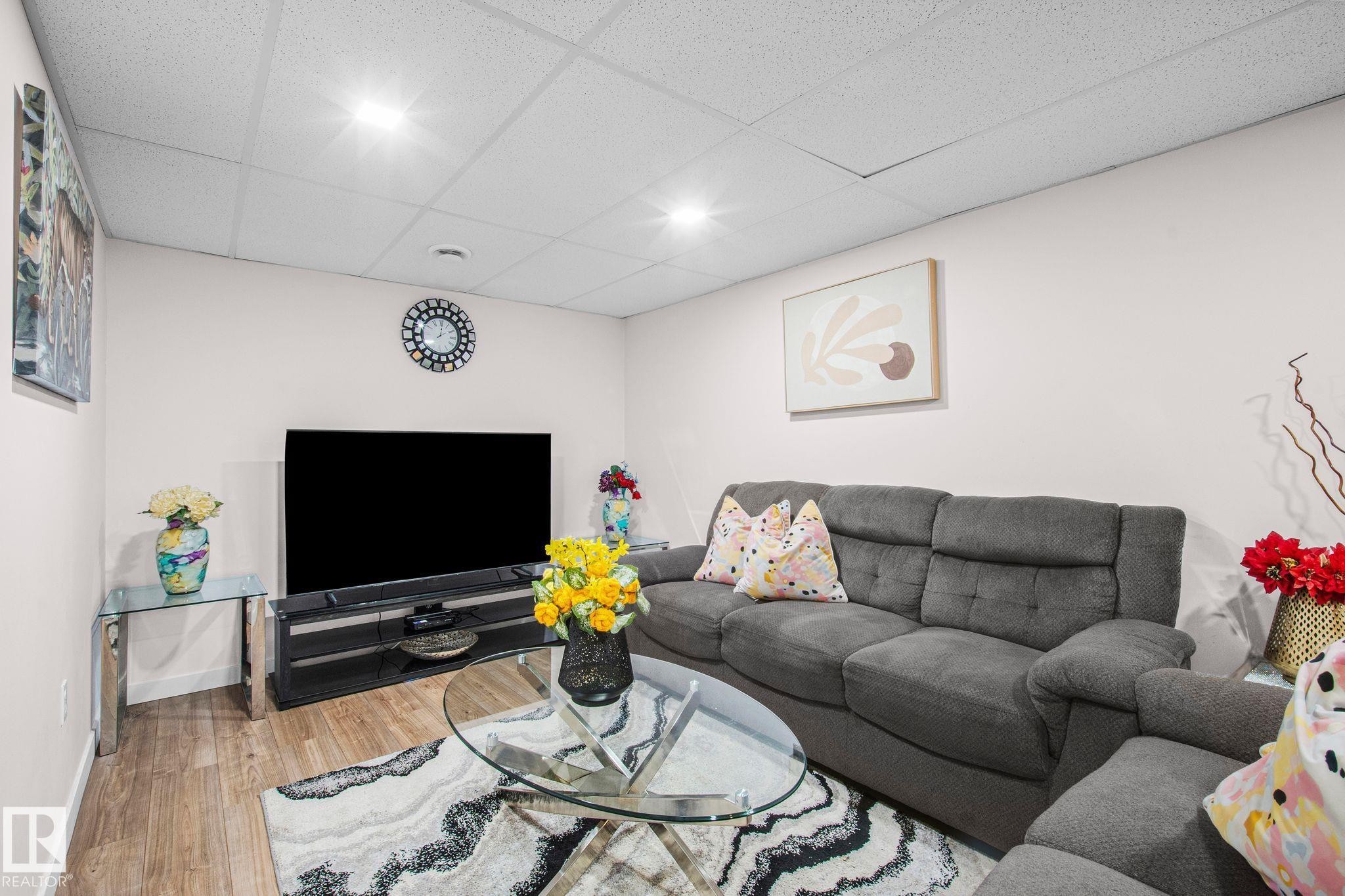 Finished living area featuring wood-finish flooring, recessed lighting, and a drop ceiling - 4806 117 Ave, Edmonton, AB