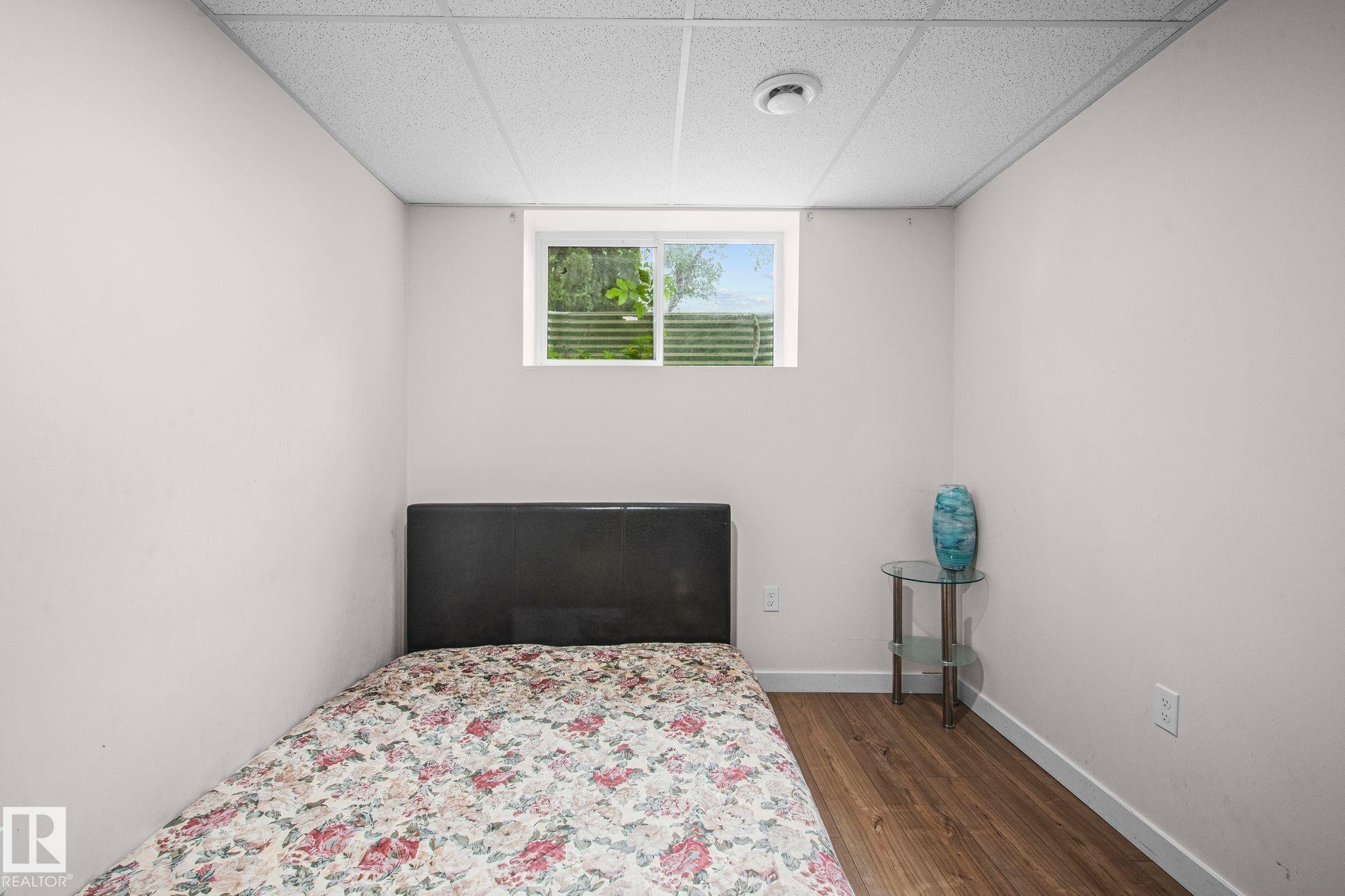 Neutral wall paint featuring a single window and wood-finish flooring - 4806 117 Ave, Edmonton, AB