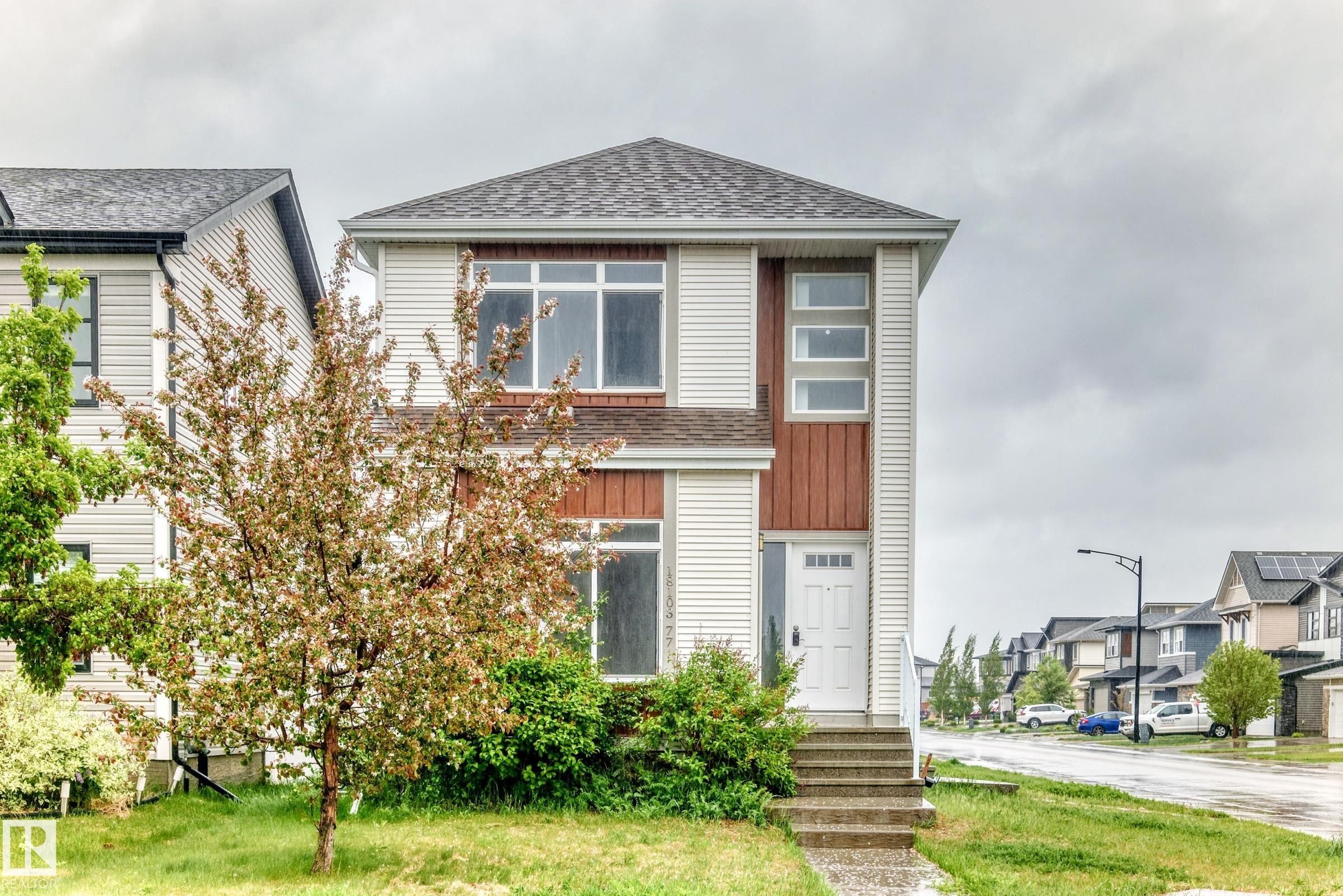 Modern two-story residence featuring light-colored siding with contrasting wood-finish accents - 18103 77 Street, Edmonton, AB