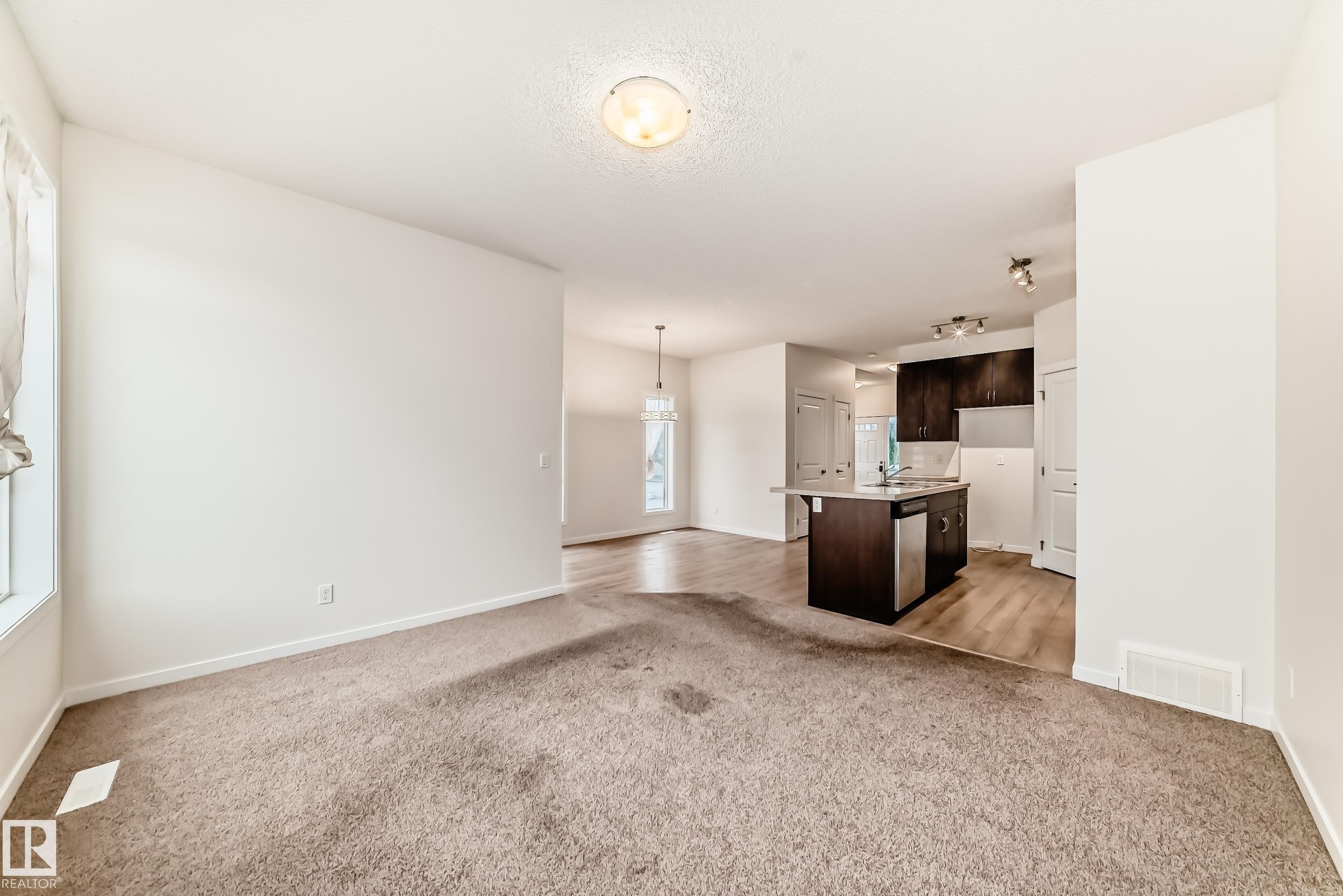 Open-concept living area with neutral carpeting and light-toned walls - 18103 77 Street, Edmonton, AB
