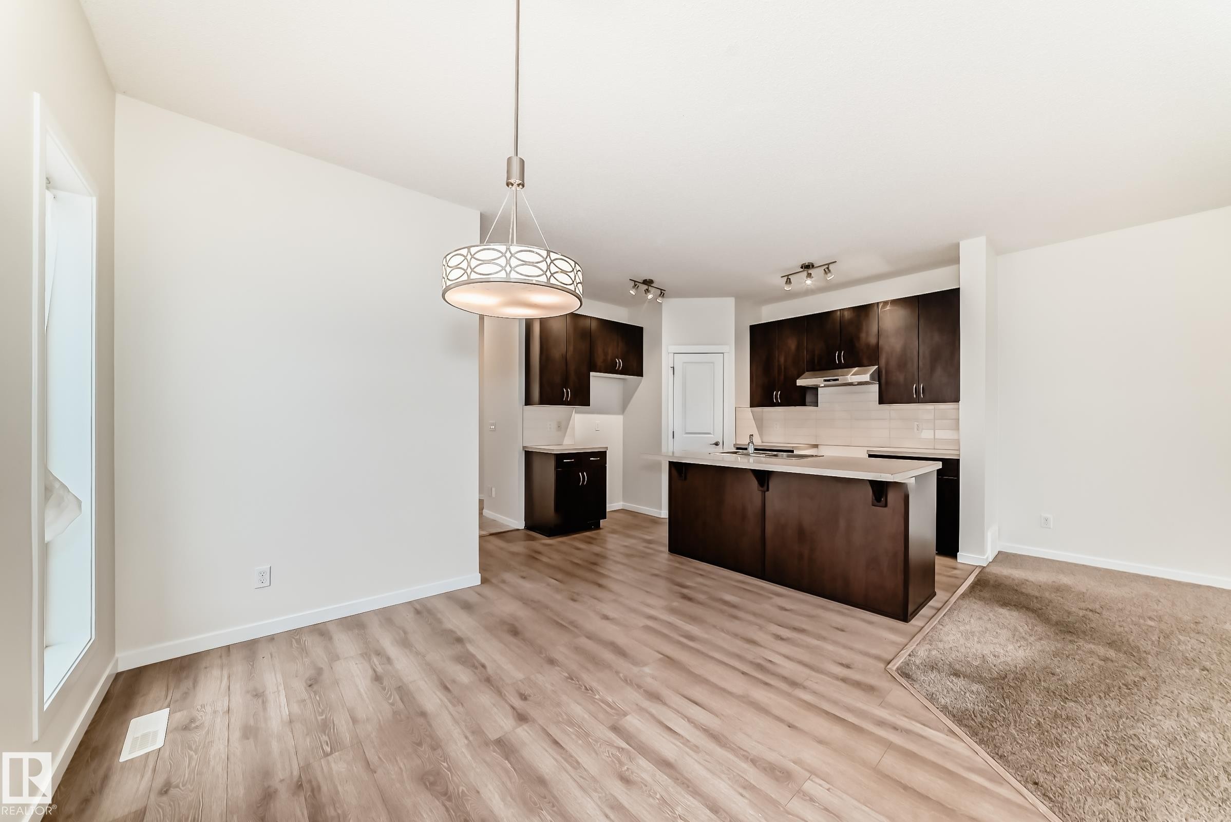 Open-concept living area featuring wood-finish flooring, a contemporary chandelier, and recessed lighting - 18103 77 Street, Edmonton, AB