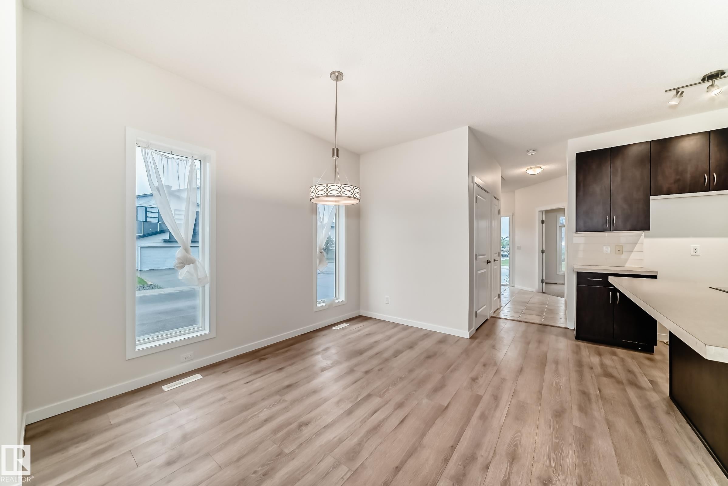 Open-concept living space with wood-finish flooring, vaulted ceilings, and ample natural light through tall windows - 18103 77 Street, Edmonton, AB
