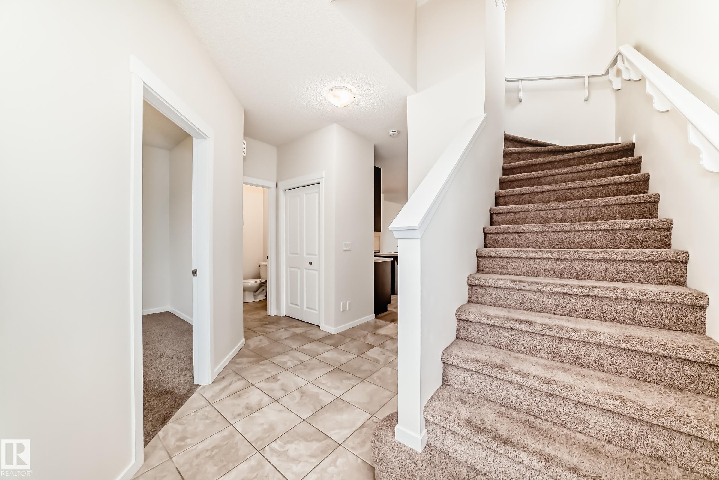 Carpeted staircase with white balusters, leading up from a tiled entryway - 18103 77 Street, Edmonton, AB