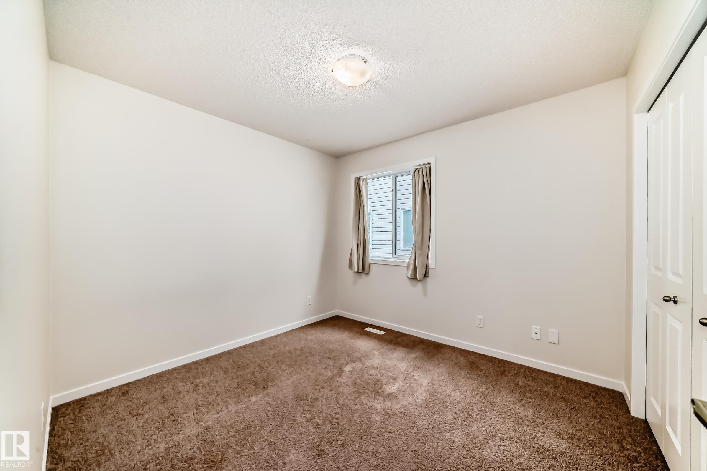 Bedroom featuring neutral wall paint, brown carpet flooring, a window with horizontal blinds, and a bi-fold closet door - 18103 77 Street, Edmonton, AB