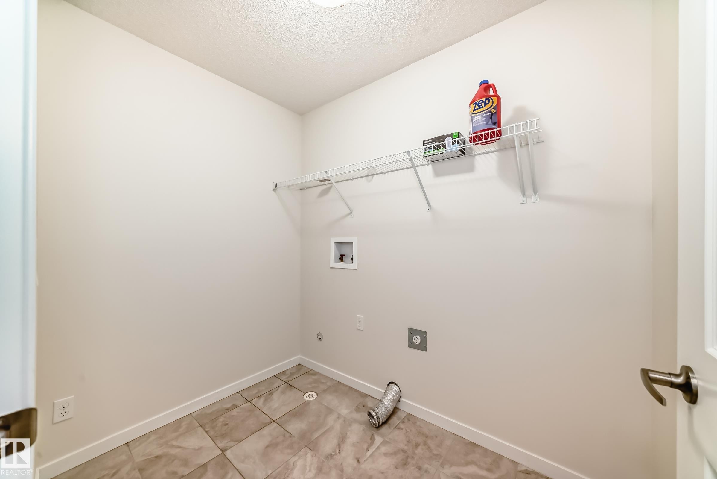 Laundry area featuring square tile flooring, white walls, and a wire shelving unit - 18103 77 Street, Edmonton, AB