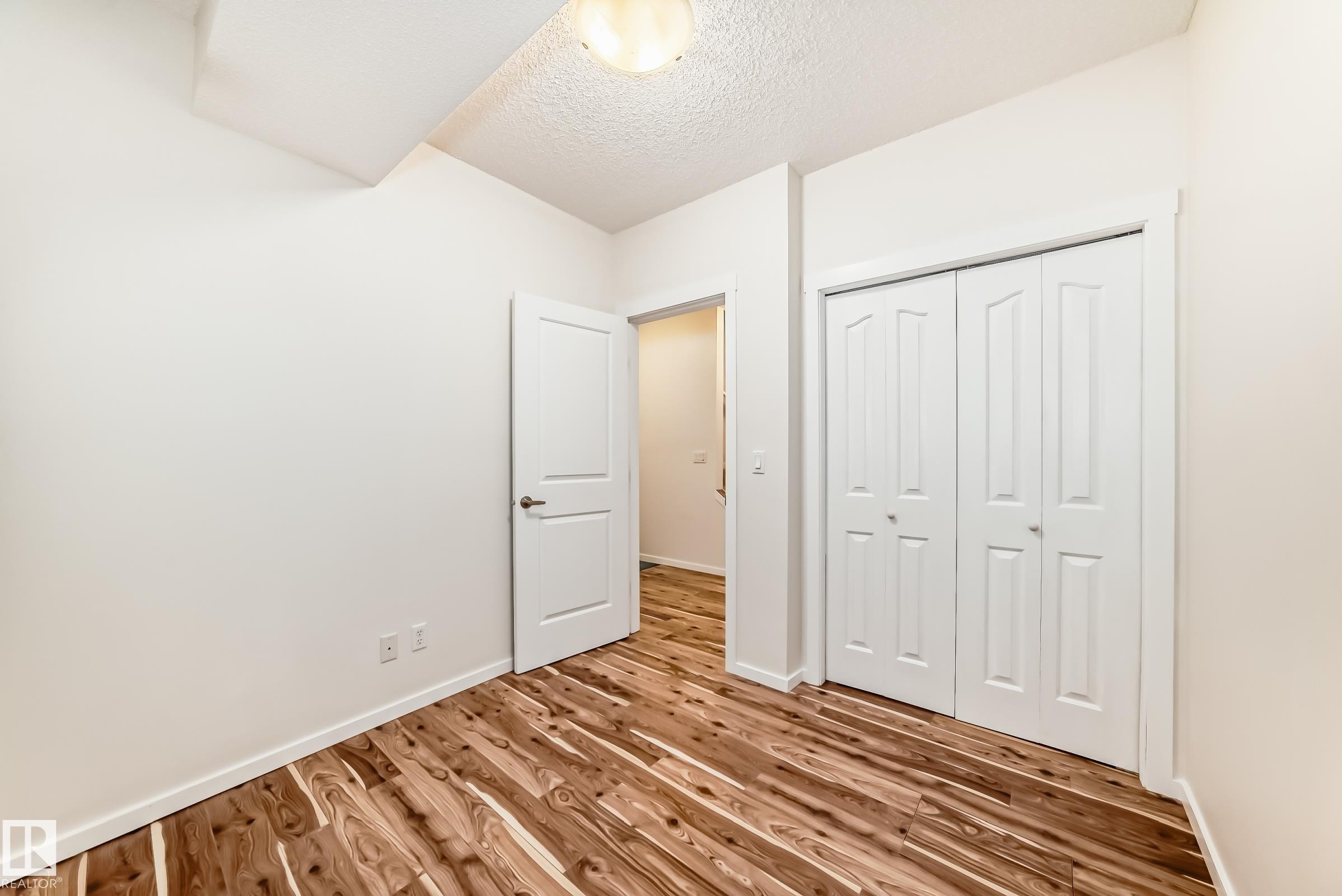 Wood-finish flooring throughout, bright white walls, and a recessed ceiling light fixture - 18103 77 Street, Edmonton, AB
