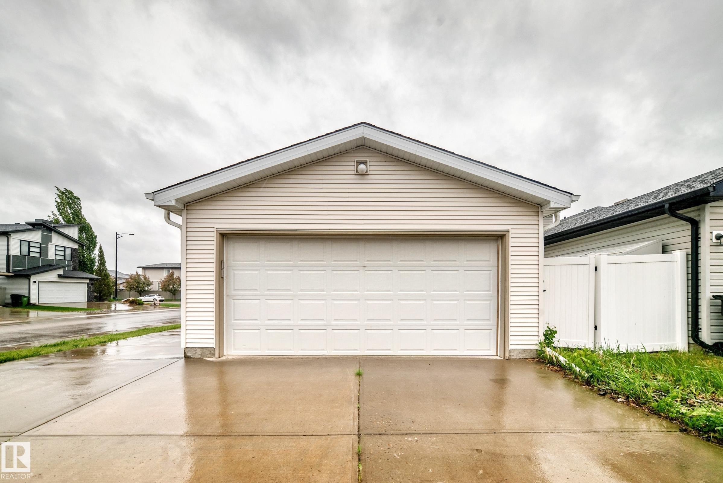Detached garage with horizontal siding, a gabled roof, and a panel garage door - 18103 77 Street, Edmonton, AB