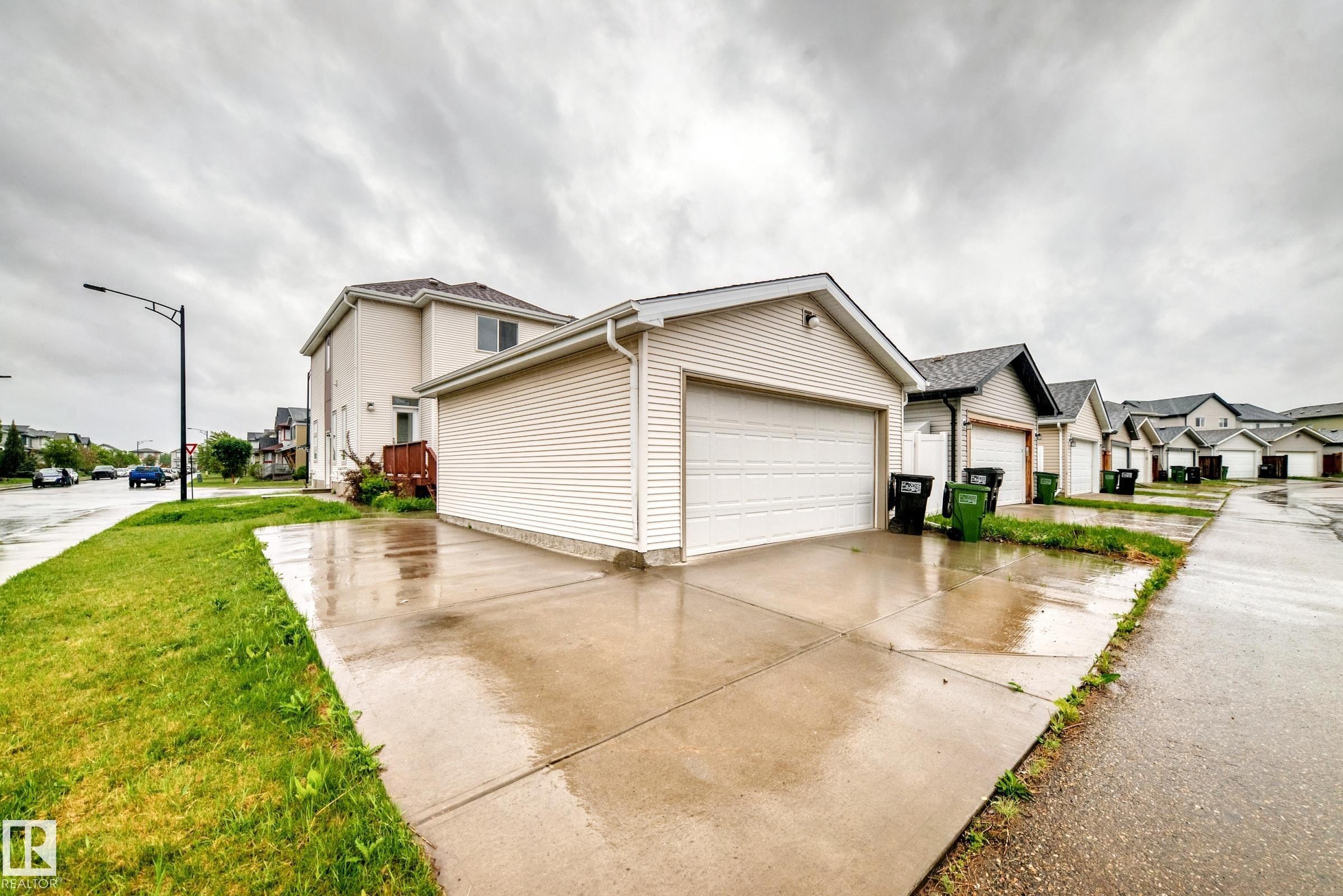 Detached garage with horizontal siding, a large white garage door, and a concrete driveway - 18103 77 Street, Edmonton, AB