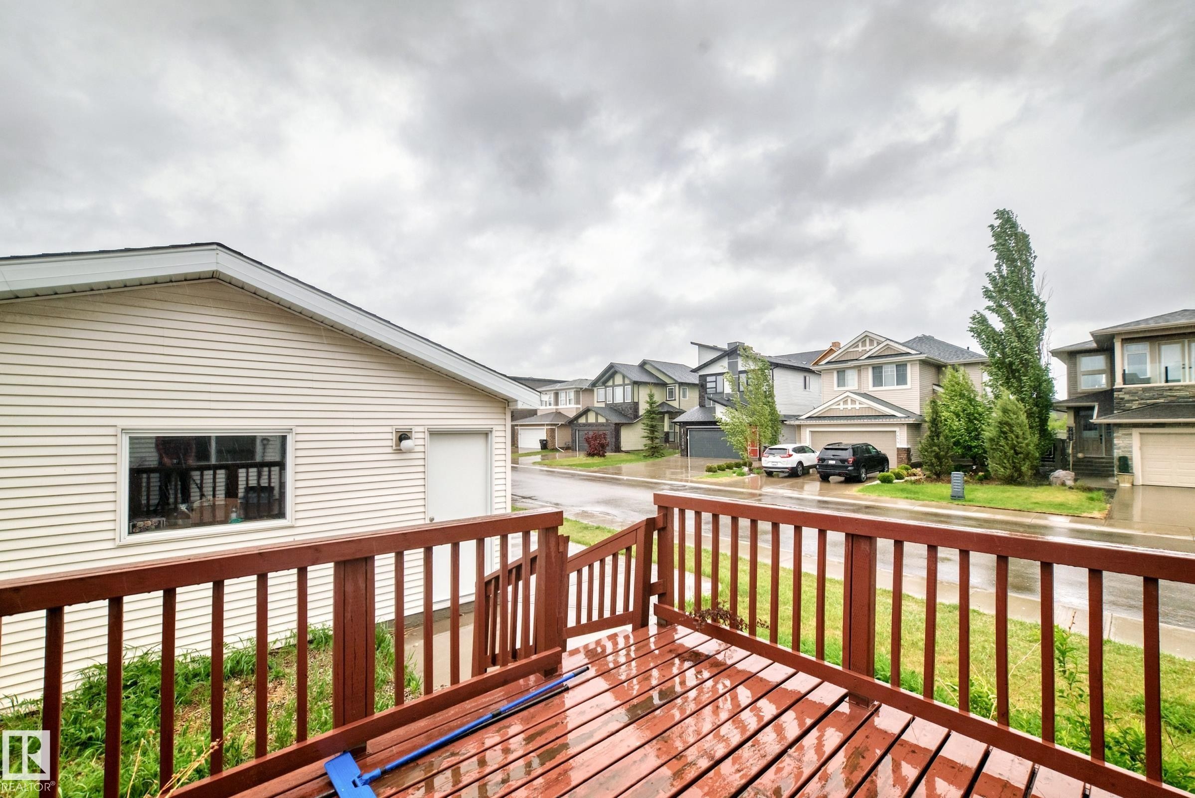 Wood-finish deck with railing overlooking a detached garage and residential street - 18103 77 Street, Edmonton, AB