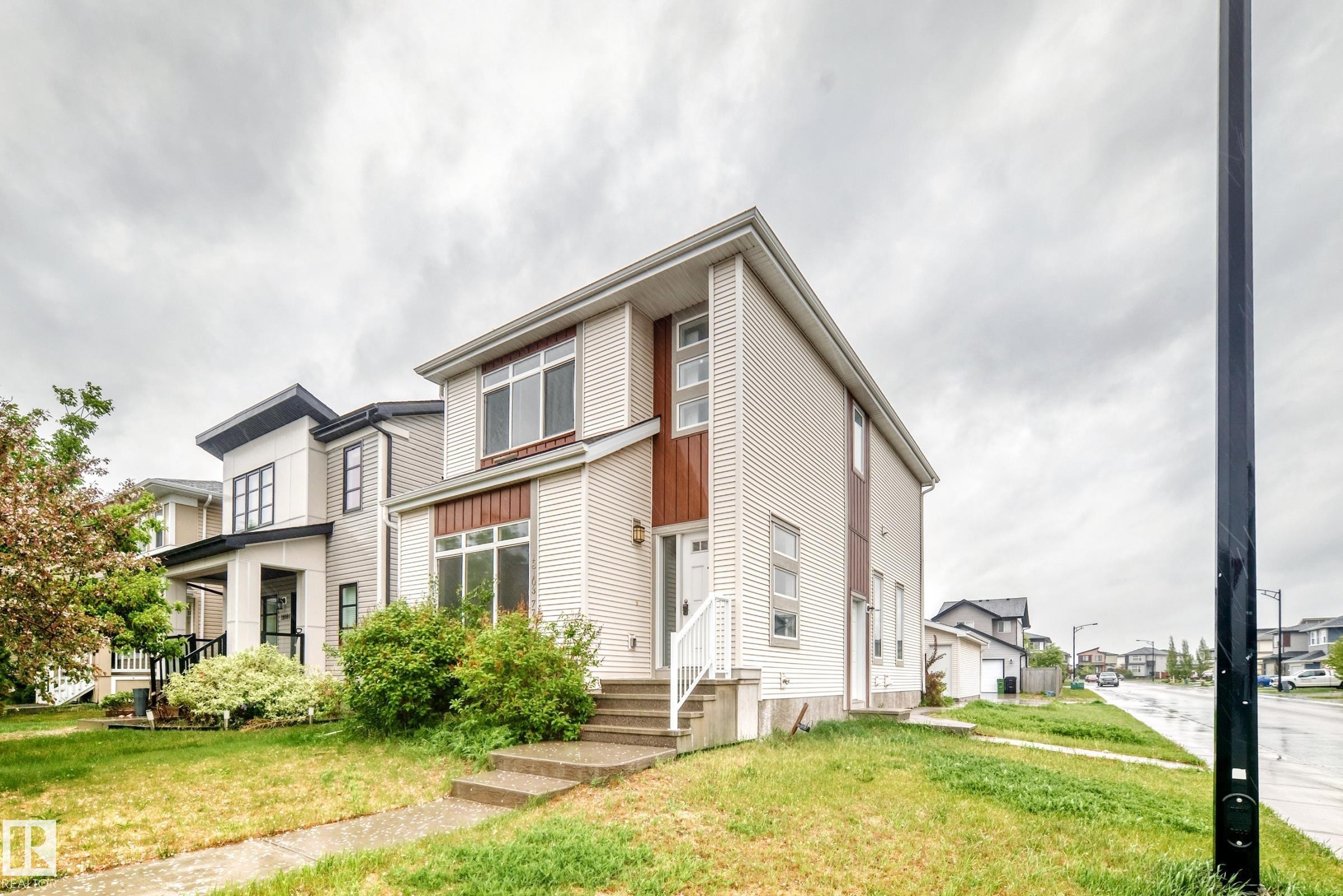Contemporary residence featuring a light-colored siding exterior, prominent multi-pane windows, and a raised entry with steps - 18103 77 Street, Edmonton, AB
