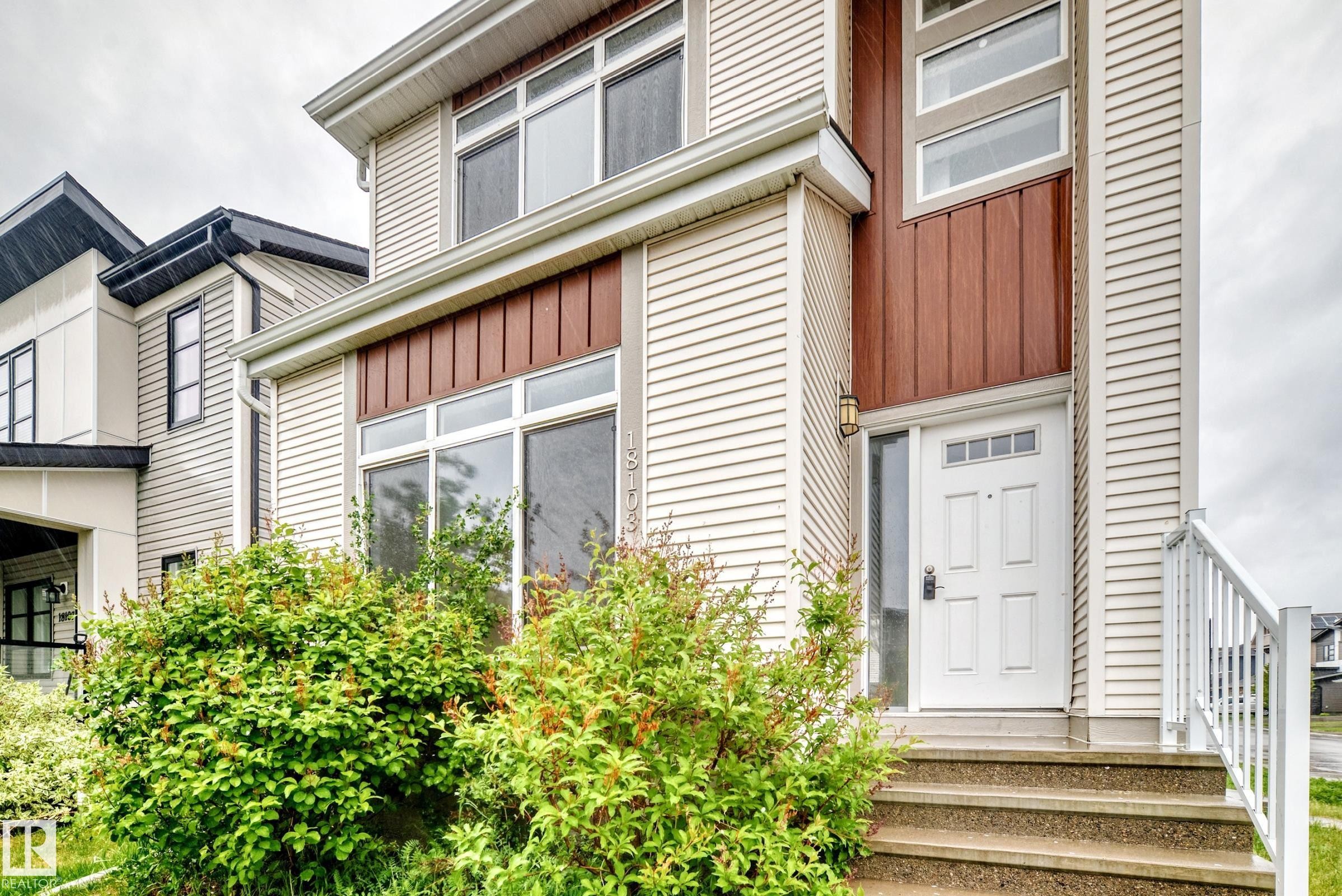 Two-story facade featuring beige horizontal siding and vertical wood-finish accents - 18103 77 Street, Edmonton, AB