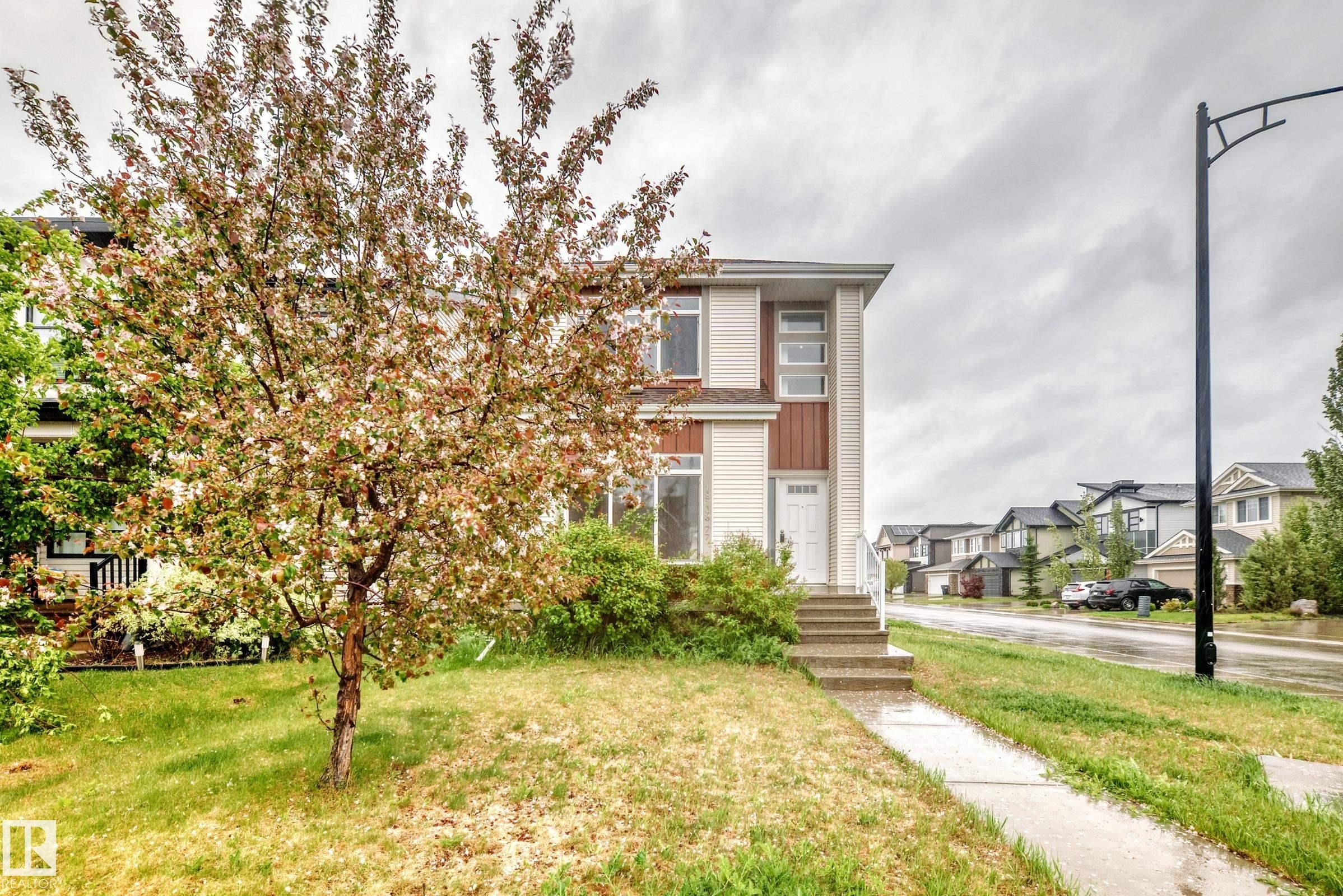 Two-story residence featuring light siding with dark trim accents and a white front door - 18103 77 Street, Edmonton, AB