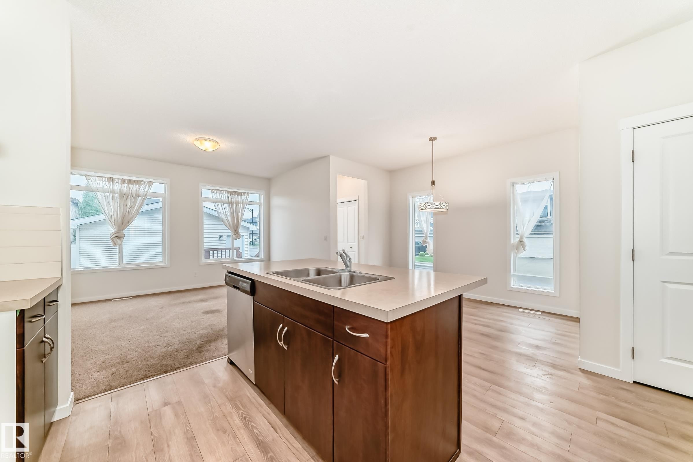 Kitchen island featuring a double-basin stainless steel sink, integrated dishwasher, and wood-finish cabinetry - 18103 77 Street, Edmonton, AB