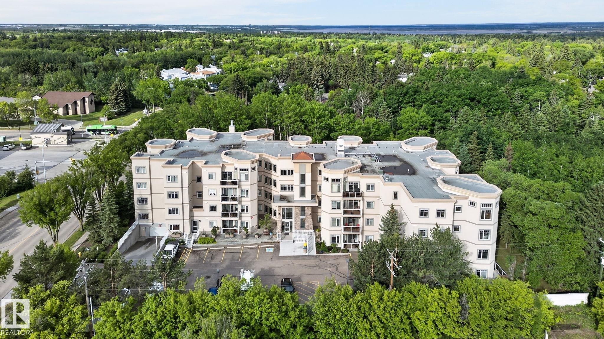 Multi-story residential building featuring a light-toned exterior finish, multiple balconies, and a curved architectural design - 208 5 Gate Avenue, St. Albert, AB