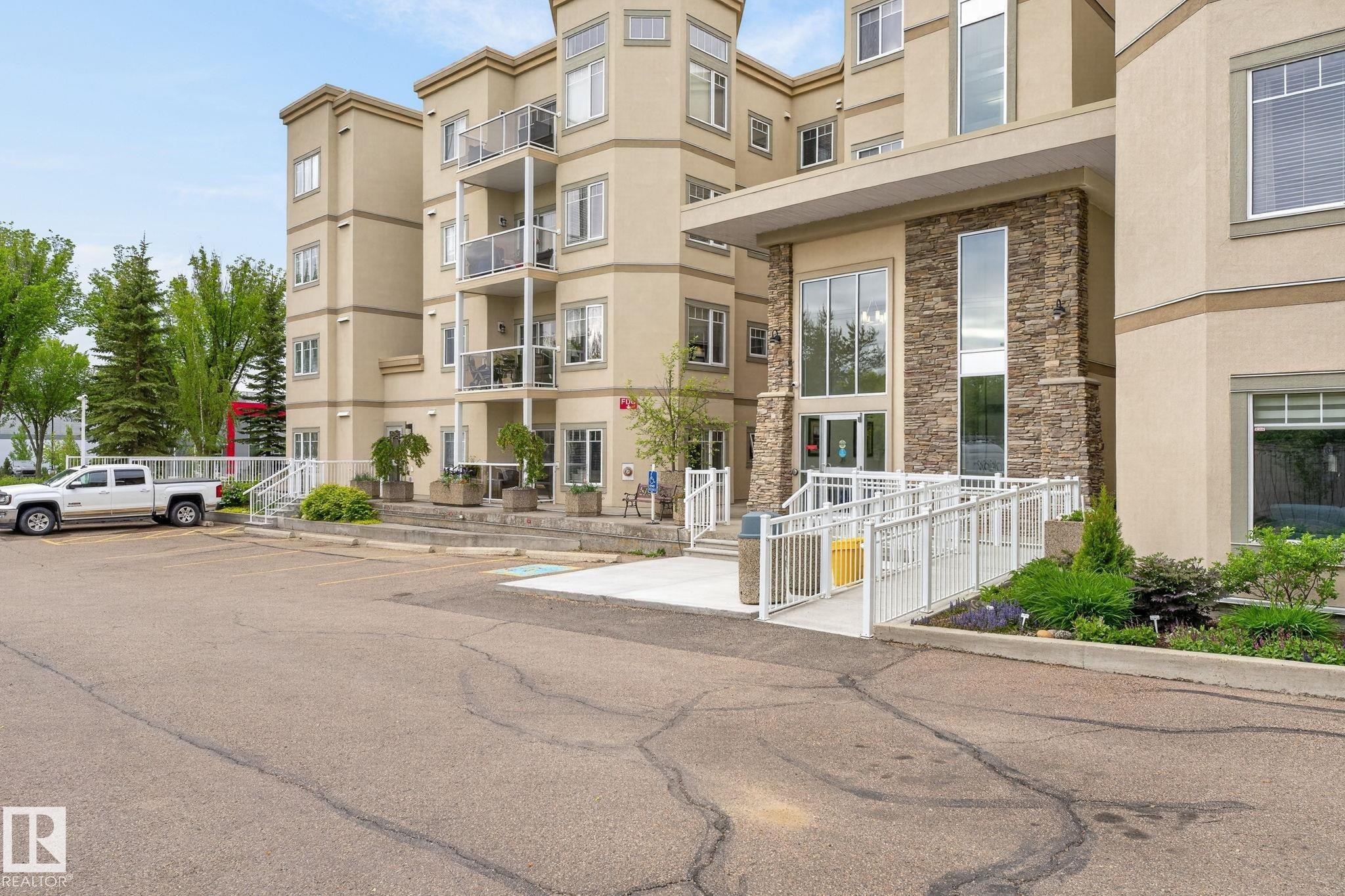 Multi-story stucco exterior featuring a prominent stone facade entrance - 208 5 Gate Avenue, St. Albert, AB