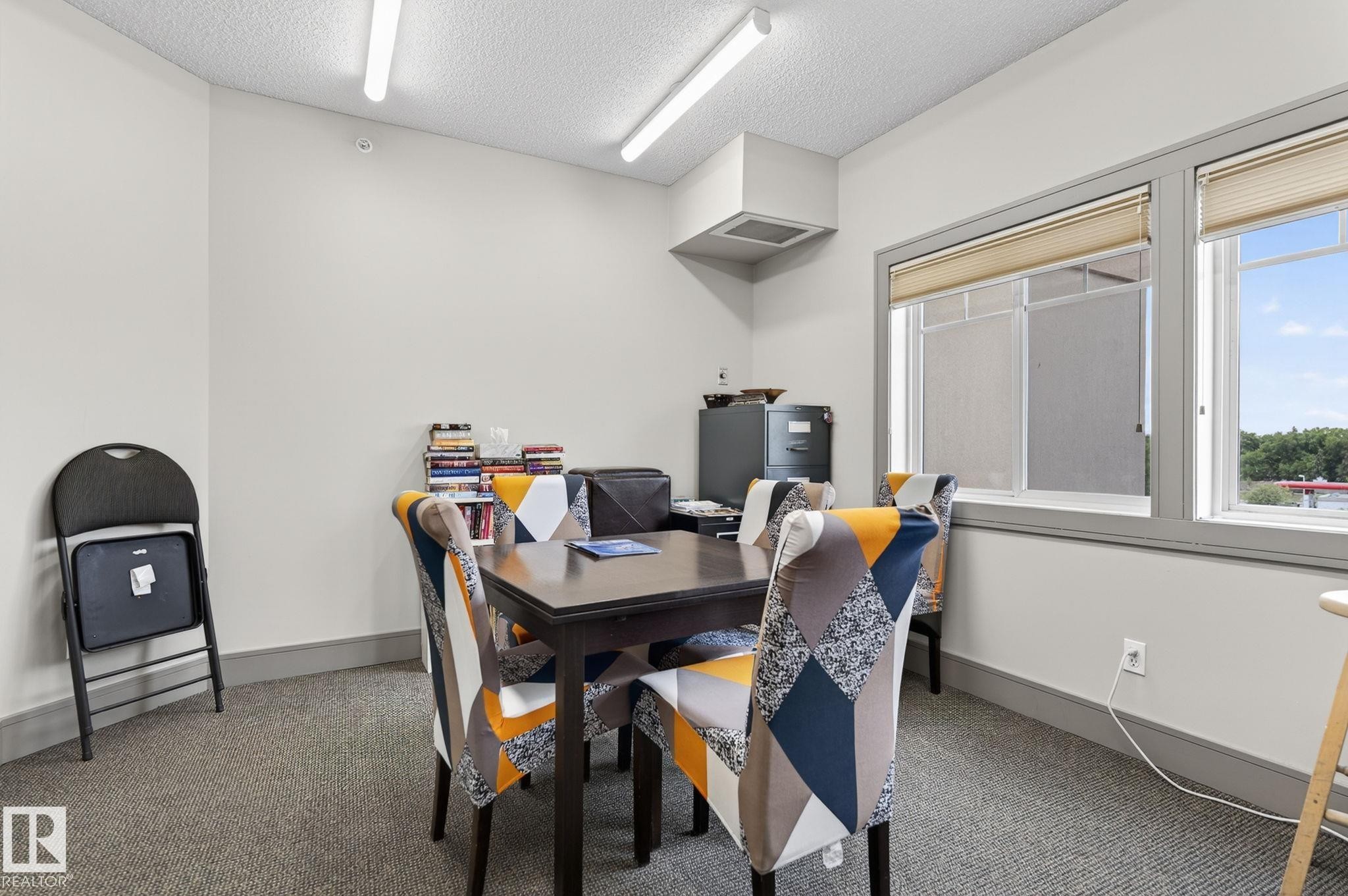 Room with carpeted flooring, white walls, and a drop ceiling with fluorescent lighting - 208 5 Gate Avenue, St. Albert, AB