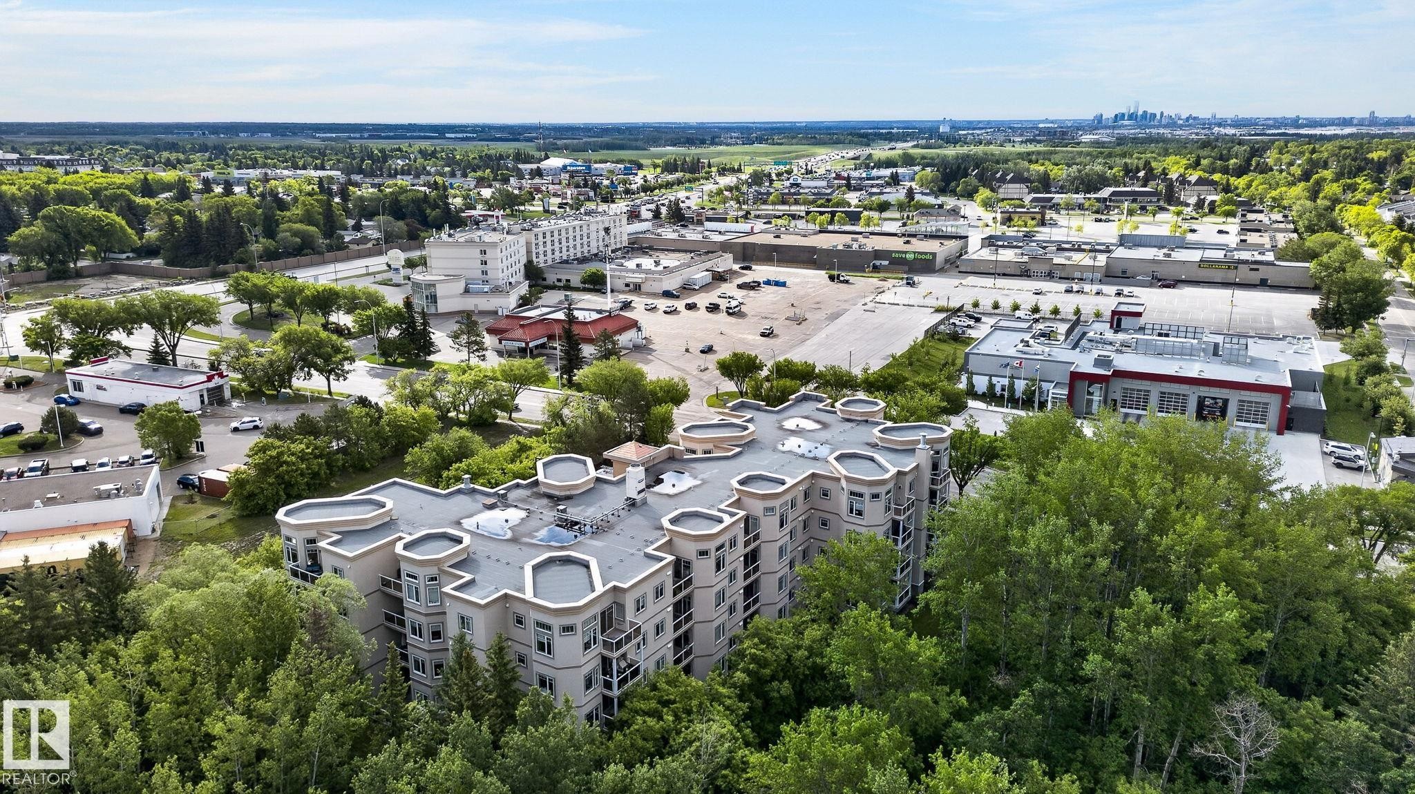 Multi-story residential building featuring a light-colored facade, numerous balconies, and a distinctive curvilinear roofline - 208 5 Gate Avenue, St. Albert, AB