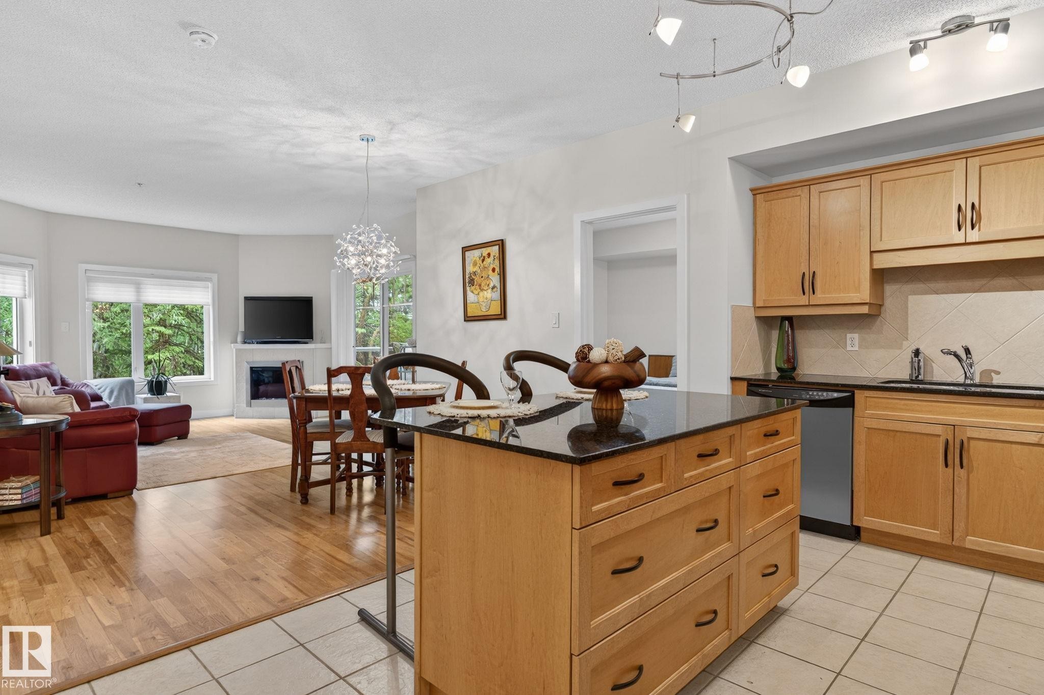 Kitchen featuring light wood cabinetry, black countertops, and tile flooring - 208 5 Gate Avenue, St. Albert, AB