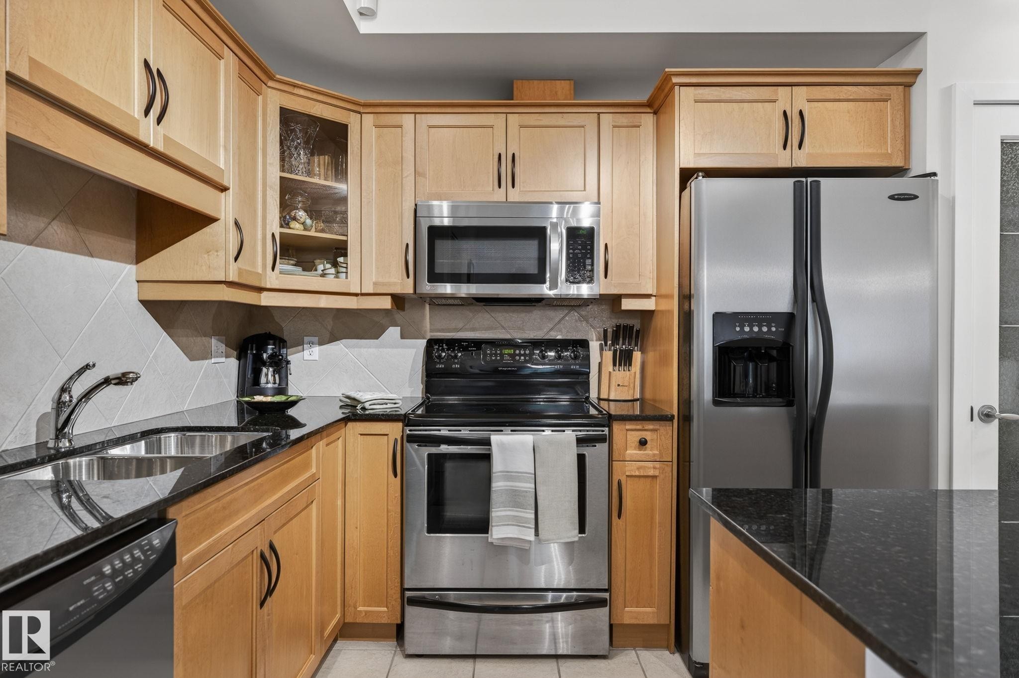 Kitchen featuring light wood cabinetry, granite-style countertops, and stainless steel appliances - 208 5 Gate Avenue, St. Albert, AB
