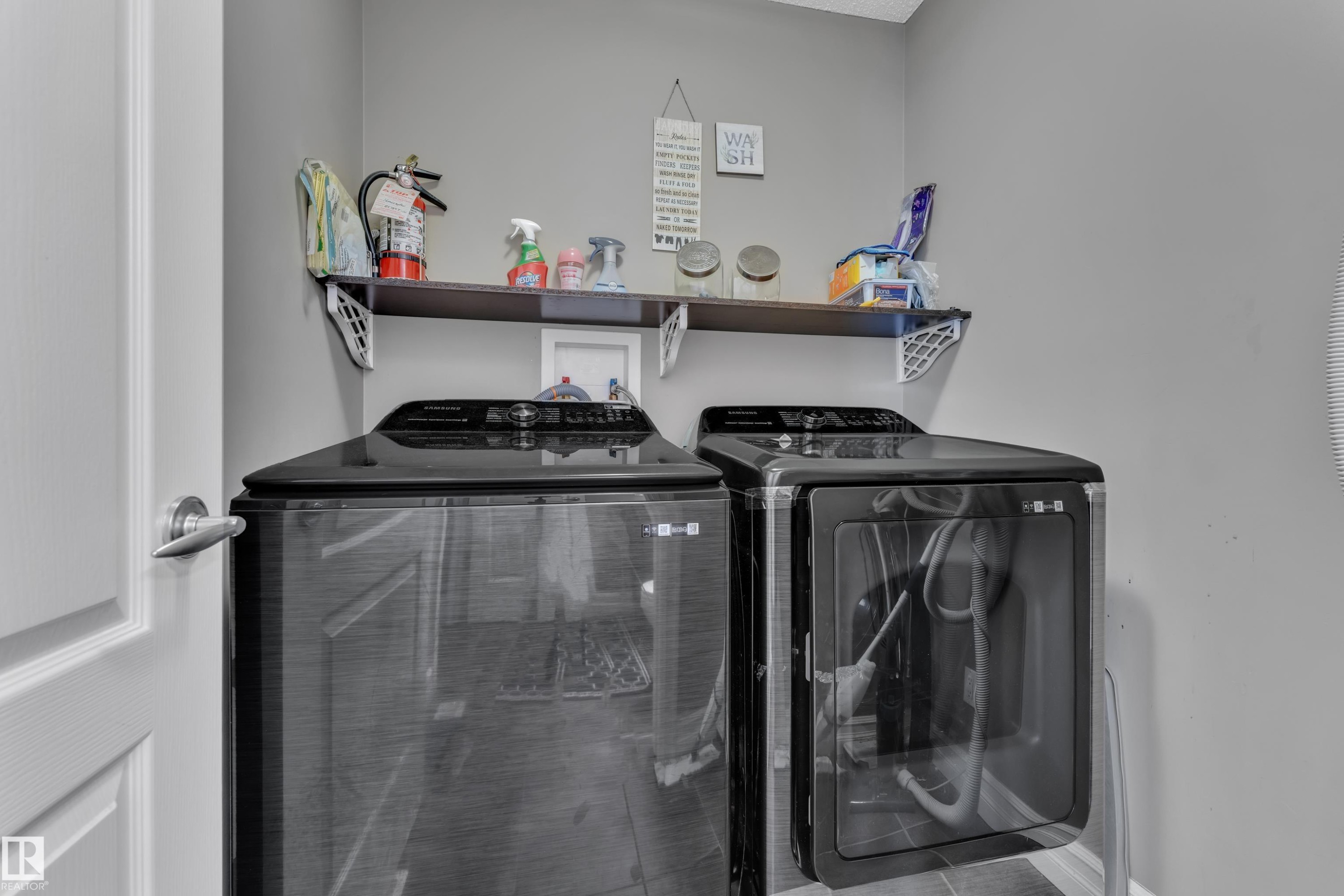 Dedicated laundry area featuring a dark wood-finish wall shelf, contemporary gray wall paint, and durable tile flooring - 6116 11 Avenue, Edmonton, AB