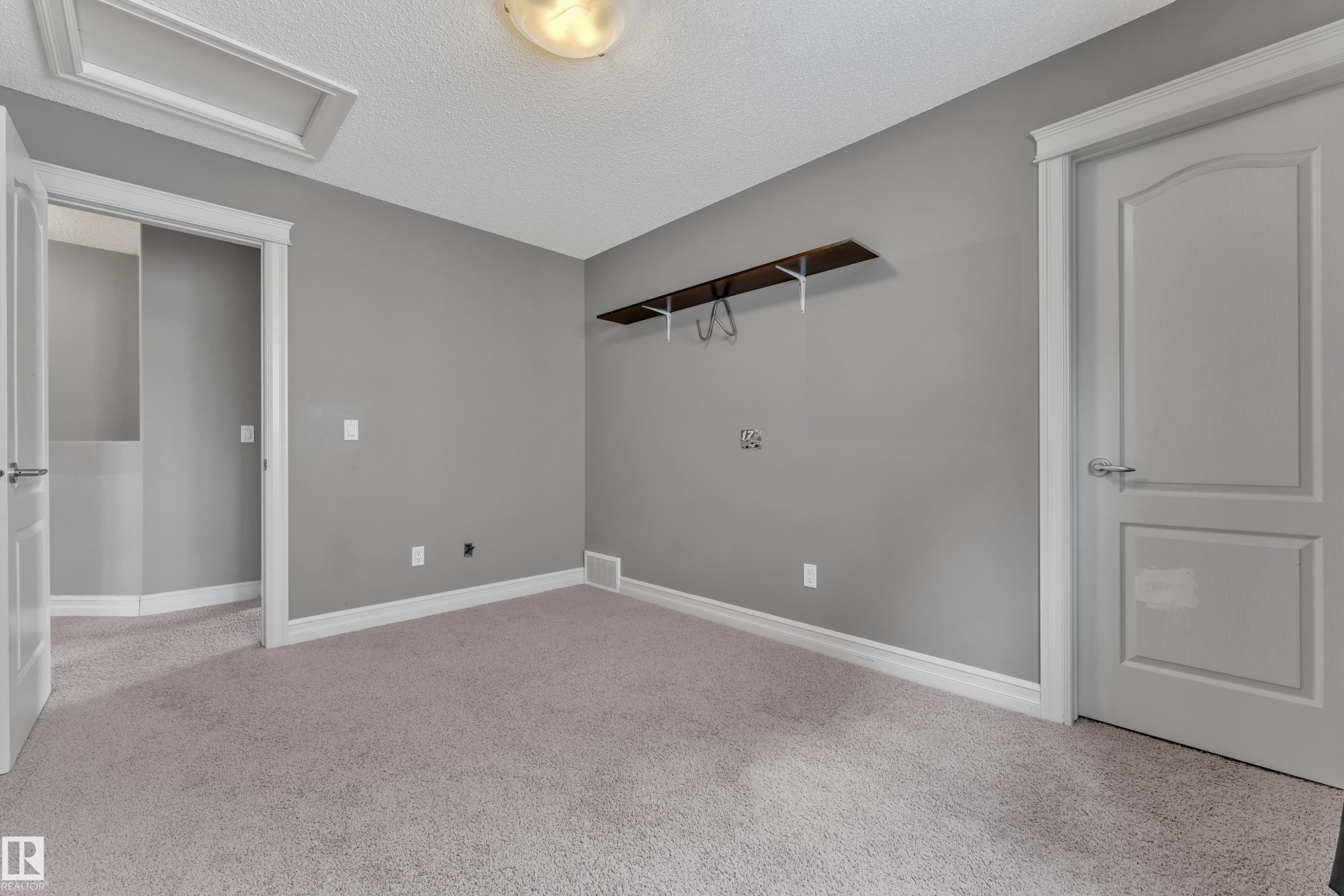 Neutral-toned room featuring a light gray carpet, matching wall paint, and white trim - 6116 11 Avenue, Edmonton, AB