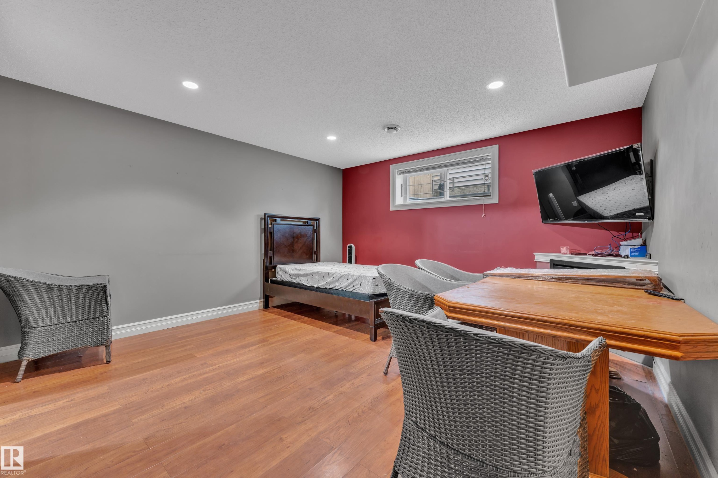 Spacious room featuring wood-finish flooring, recessed lighting, and a window with blinds - 6116 11 Avenue, Edmonton, AB