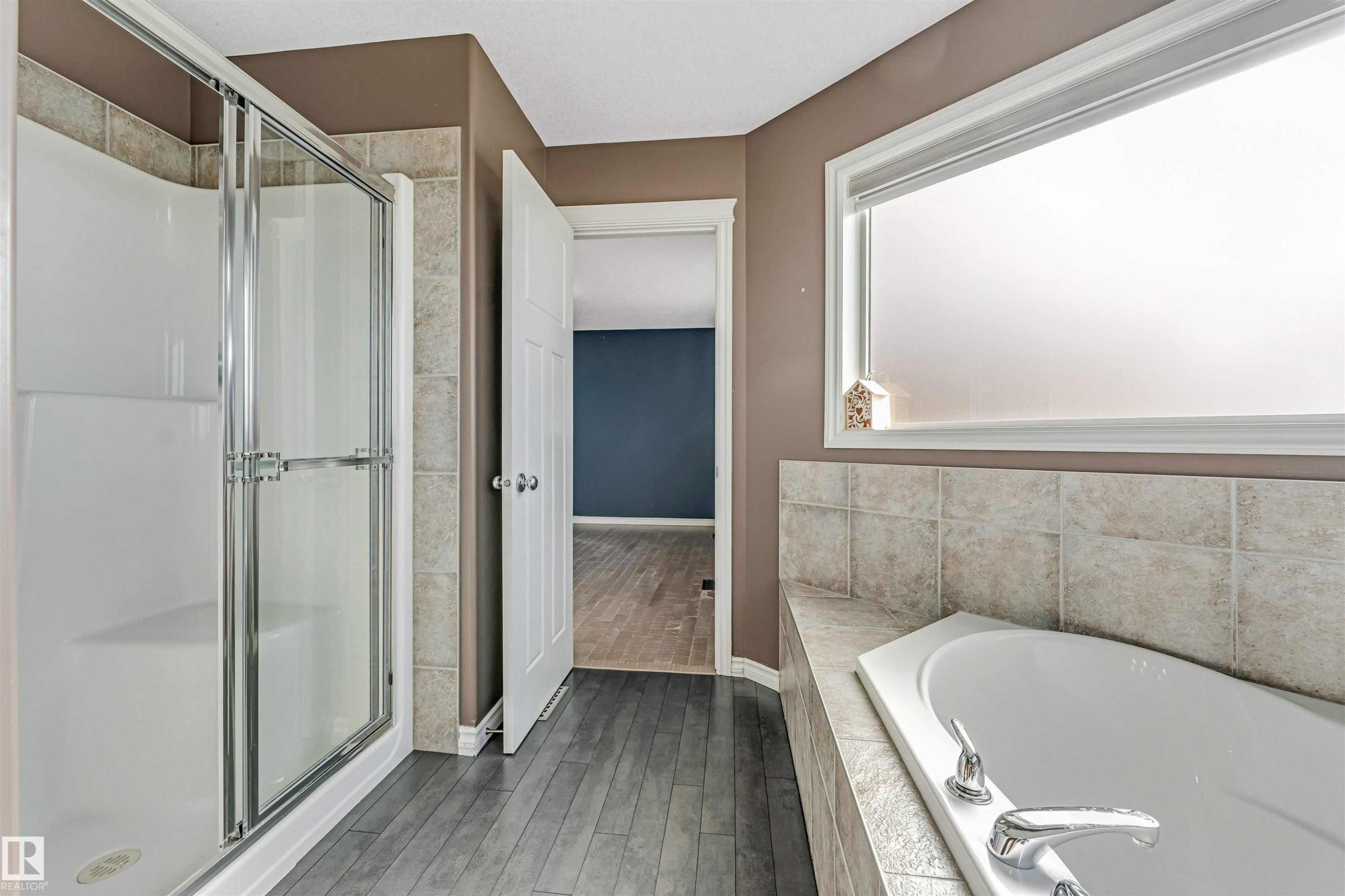 Corner soaking tub with light-toned tile surround and chrome fixtures - 5928 12 Avenue, Edmonton, AB