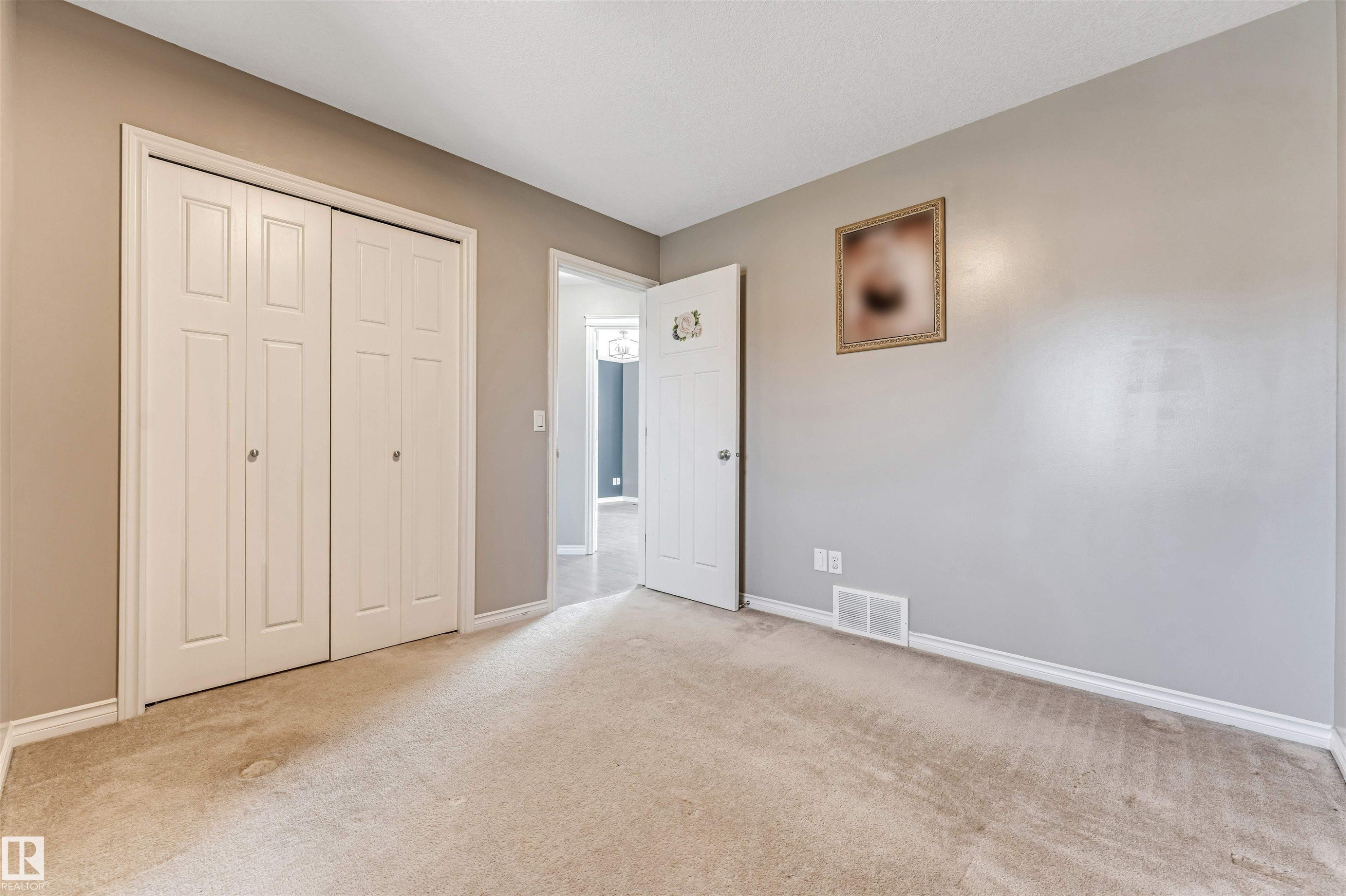 Neutral-toned room featuring a soft carpeted floor and white baseboards - 5928 12 Avenue, Edmonton, AB
