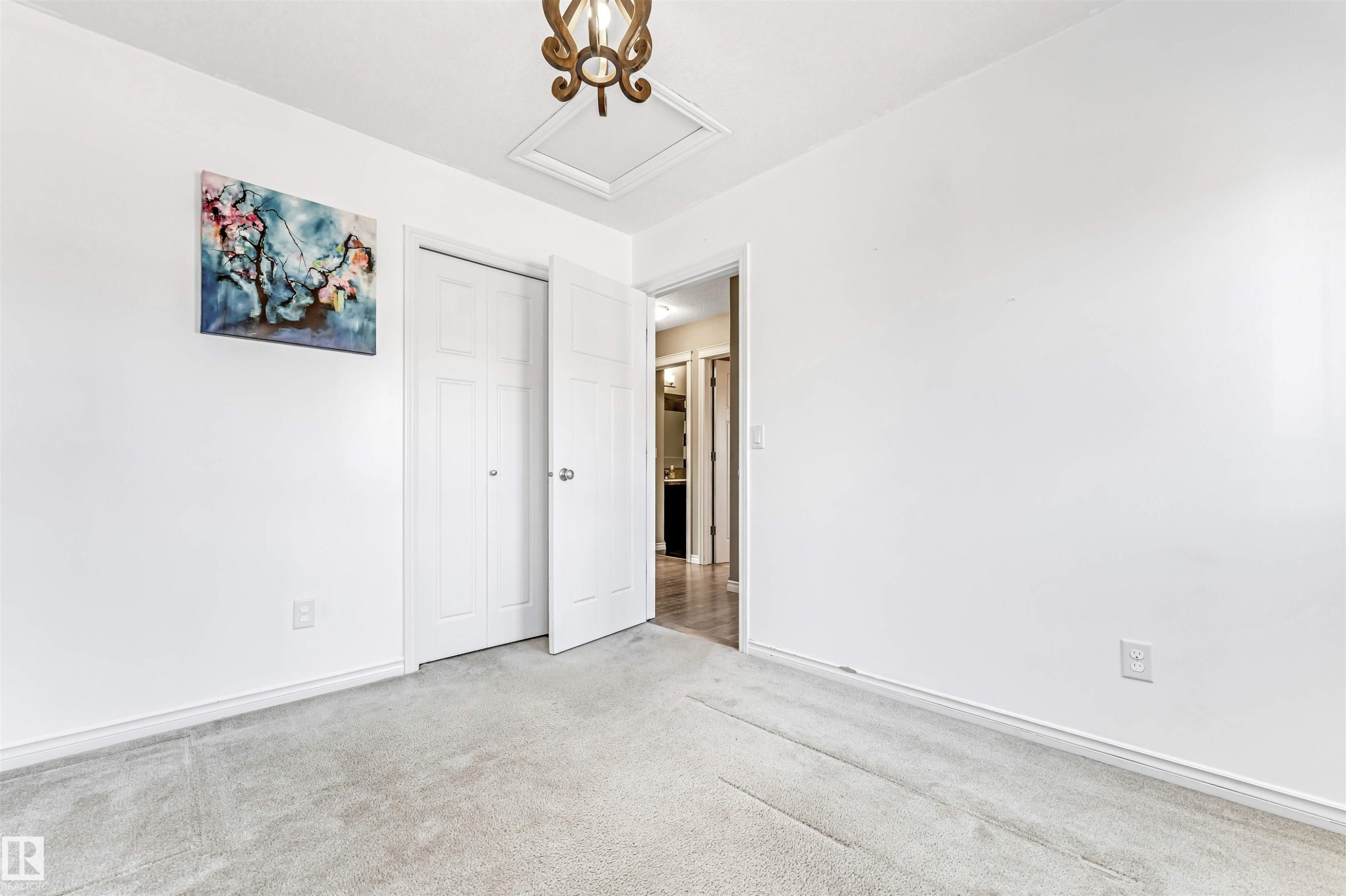 Room featuring neutral-toned carpeting, white walls, and a bi-fold closet - 5928 12 Avenue, Edmonton, AB