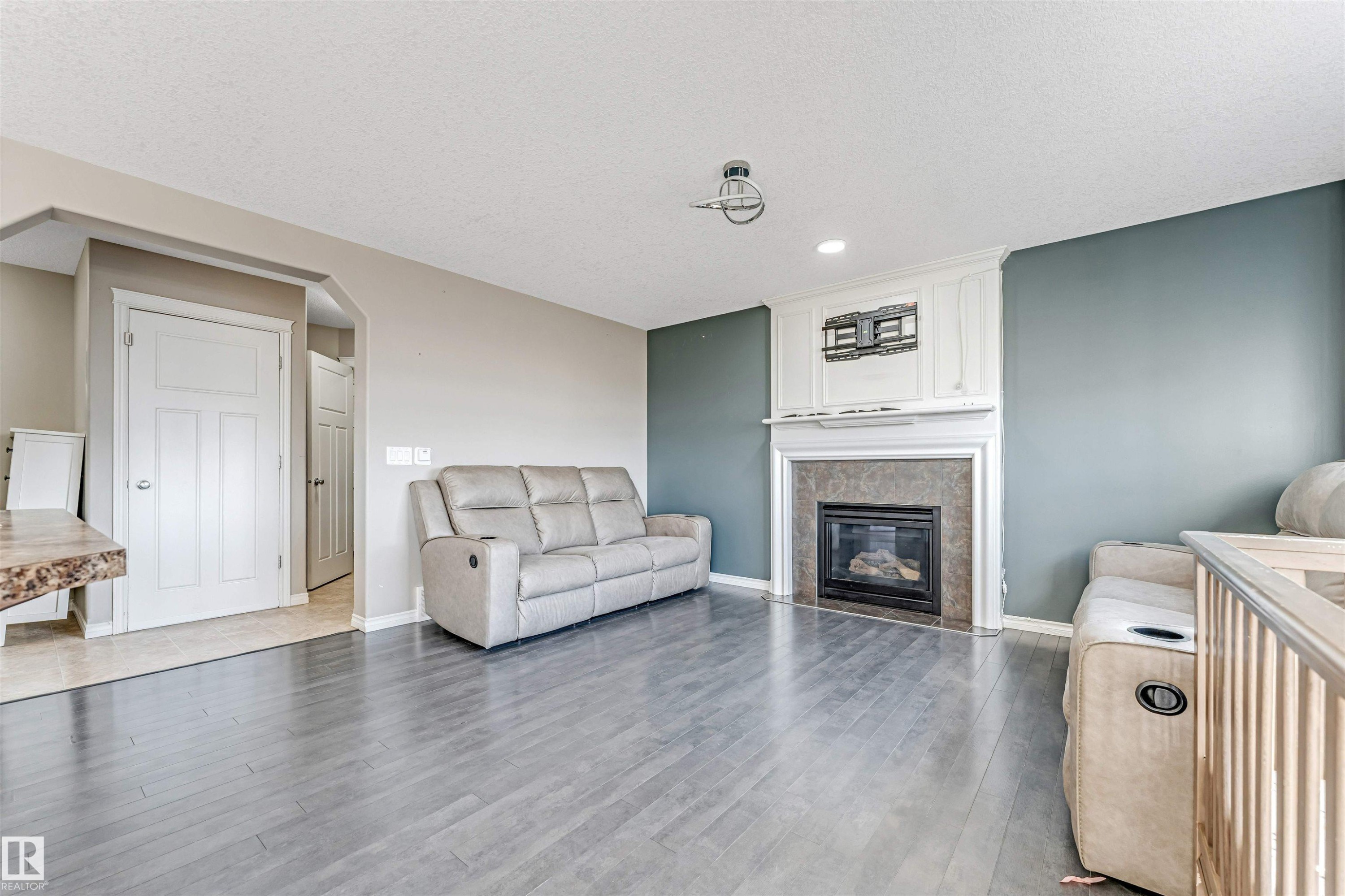 Living area featuring a fireplace with a mantel, tile surround, and white trim - 5928 12 Avenue, Edmonton, AB