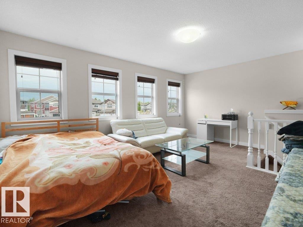 Spacious room featuring three windows, neutral wall tones, and plush carpeting - 3756 8 Street, Edmonton, AB