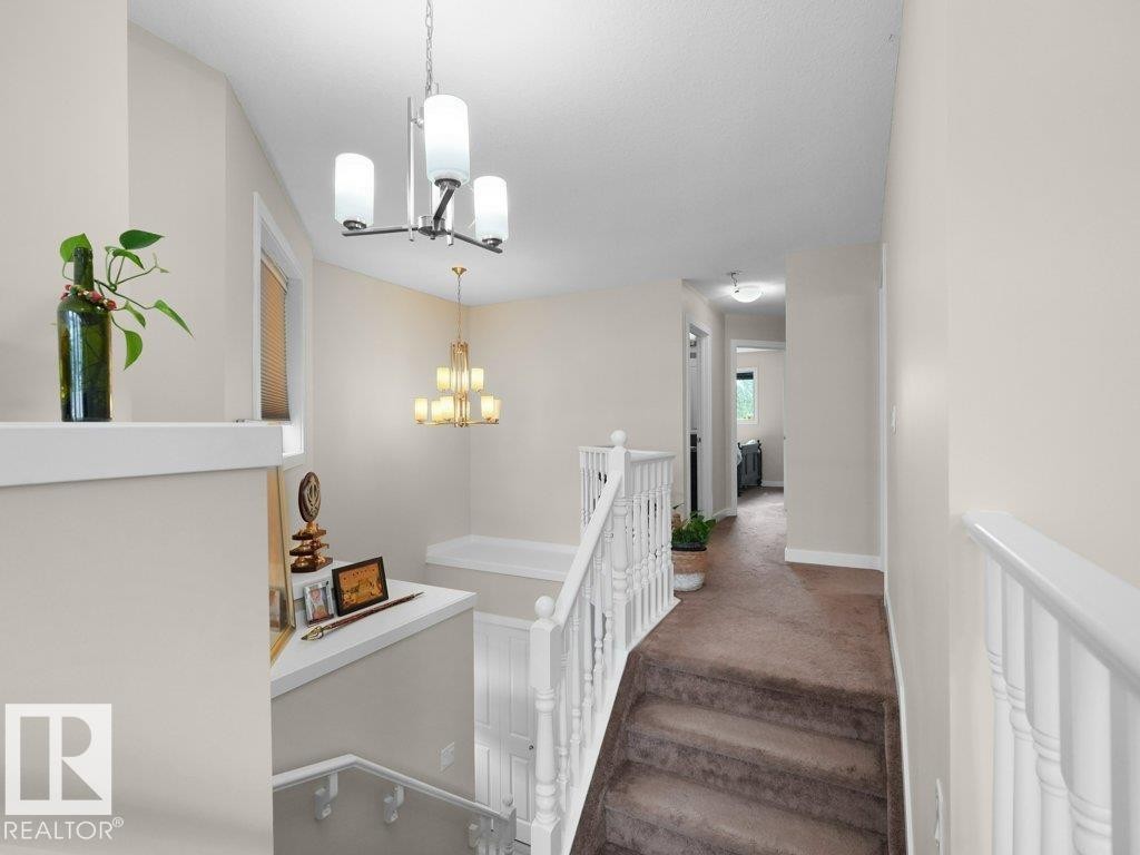 Upper-level hallway featuring neutral wall paint, white trim, and a carpeted staircase - 3756 8 Street, Edmonton, AB