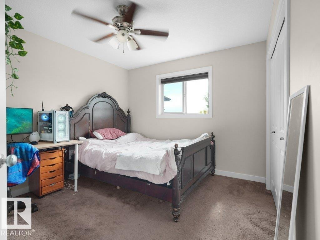 Carpeted room featuring a ceiling fan with integrated lighting, a window with a dark frame, and white trim throughout - 3756 8 Street, Edmonton, AB