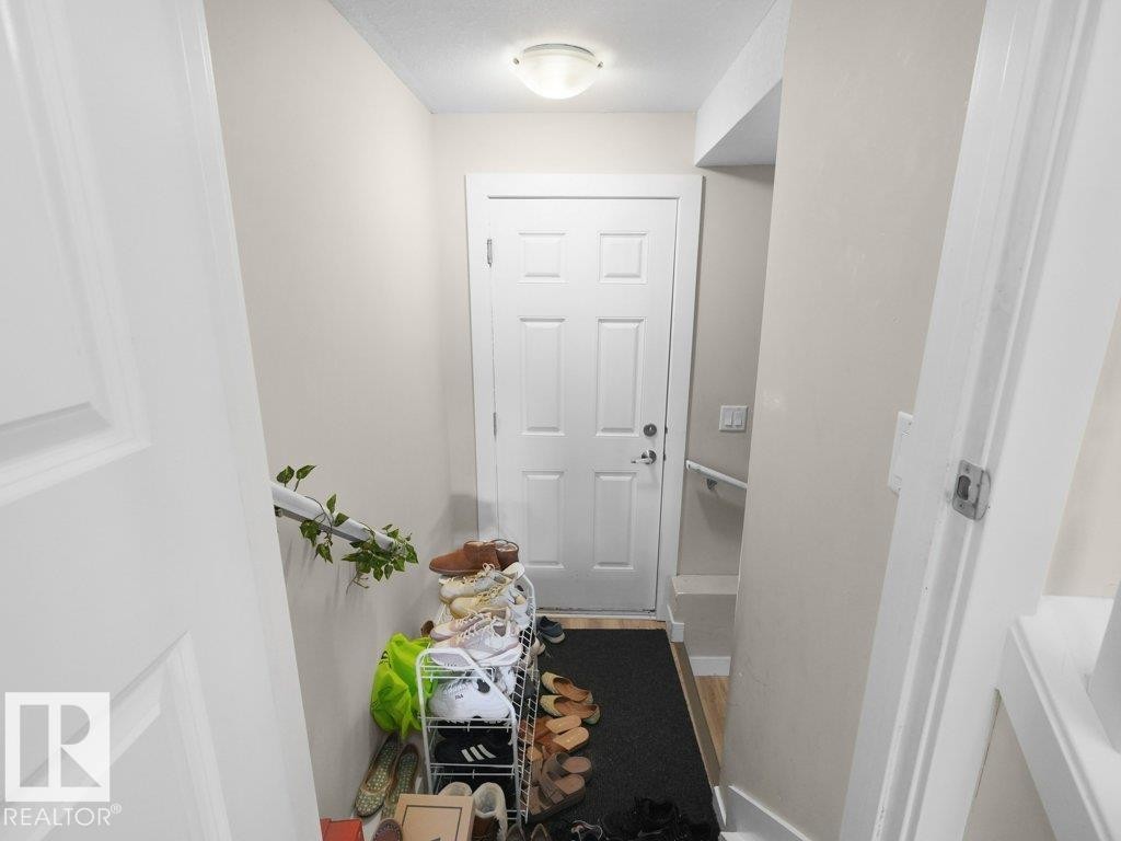 Entryway featuring a paneled door, flush-mount ceiling light, light beige wall paint, white trim, and wood-finish flooring - 3756 8 Street, Edmonton, AB