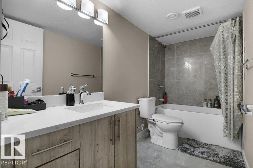 Full bathroom featuring a wood-finish vanity with an integrated sink, polished chrome faucet, and a large vanity mirror - 3756 8 Street, Edmonton, AB