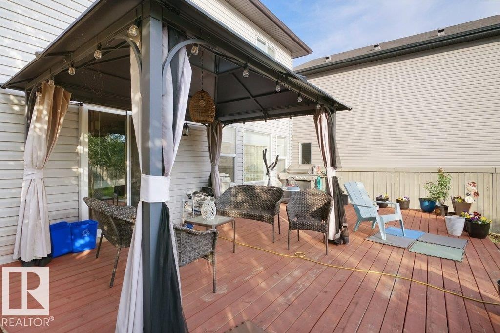 Spacious outdoor deck featuring red-toned wood flooring and a covered gazebo - 3756 8 Street, Edmonton, AB