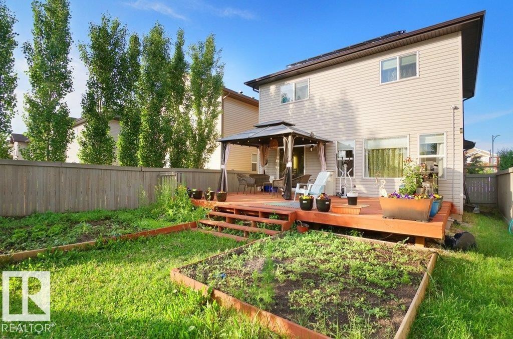 Expansive backyard featuring a multi-level wood deck, a covered gazebo, and two raised garden beds - 3756 8 Street, Edmonton, AB