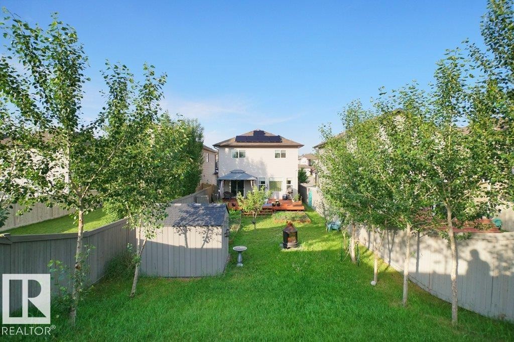 Expansive backyard featuring a manicured lawn, established trees, and a wooden privacy fence - 3756 8 Street, Edmonton, AB